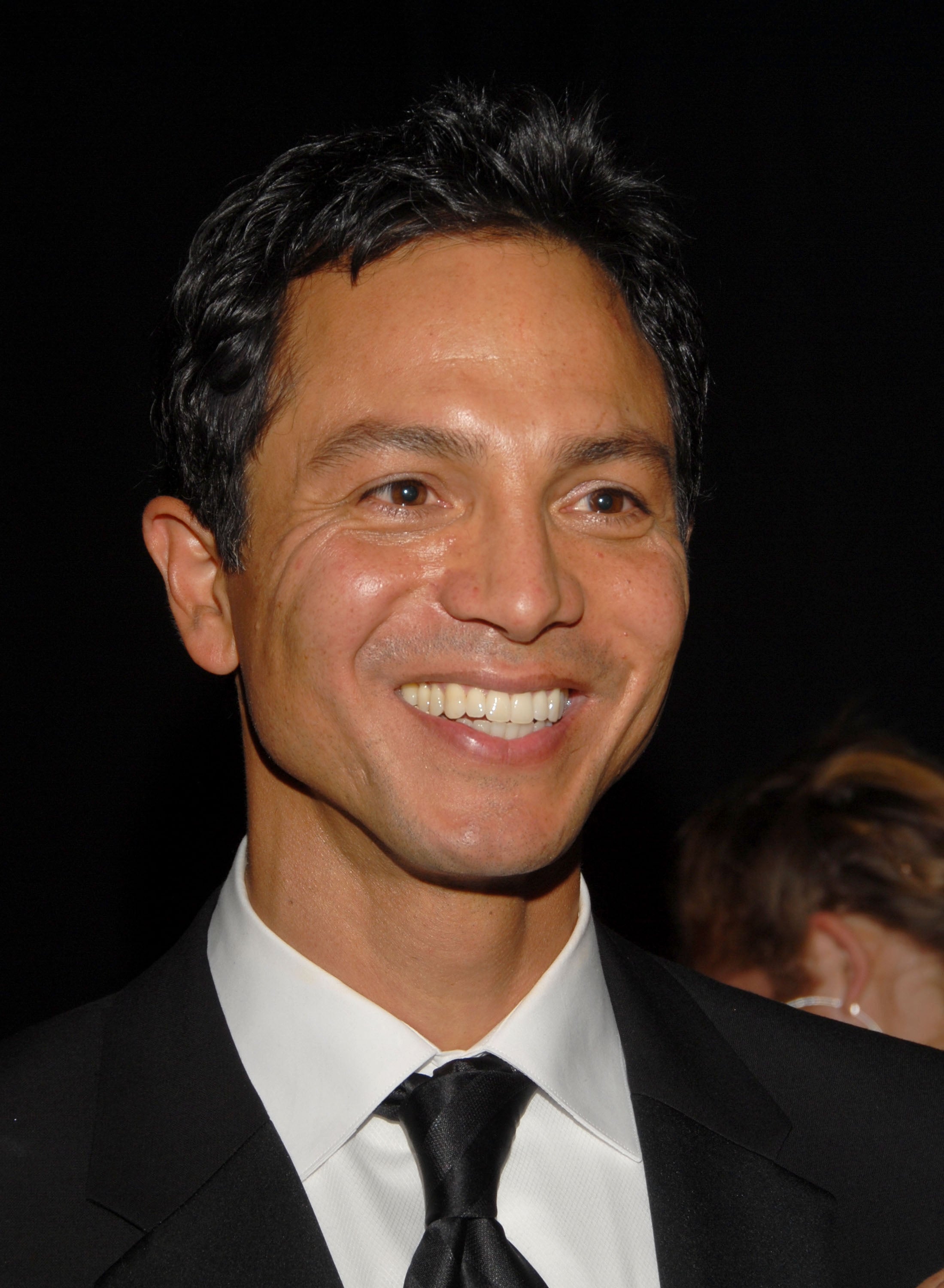Man in a black suit and tie smiling at an event