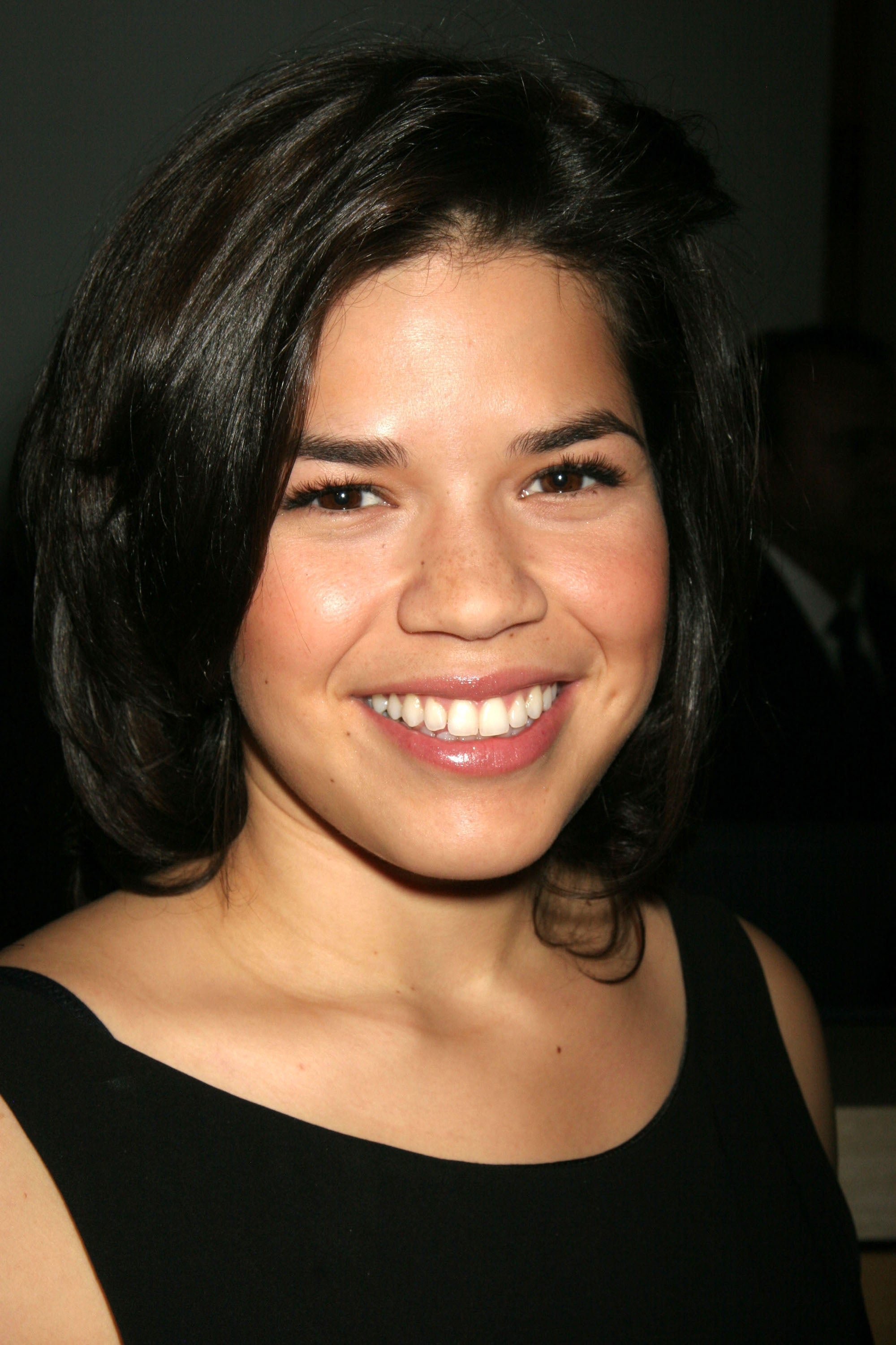 Person smiling while wearing a simple, elegant black dress at an event