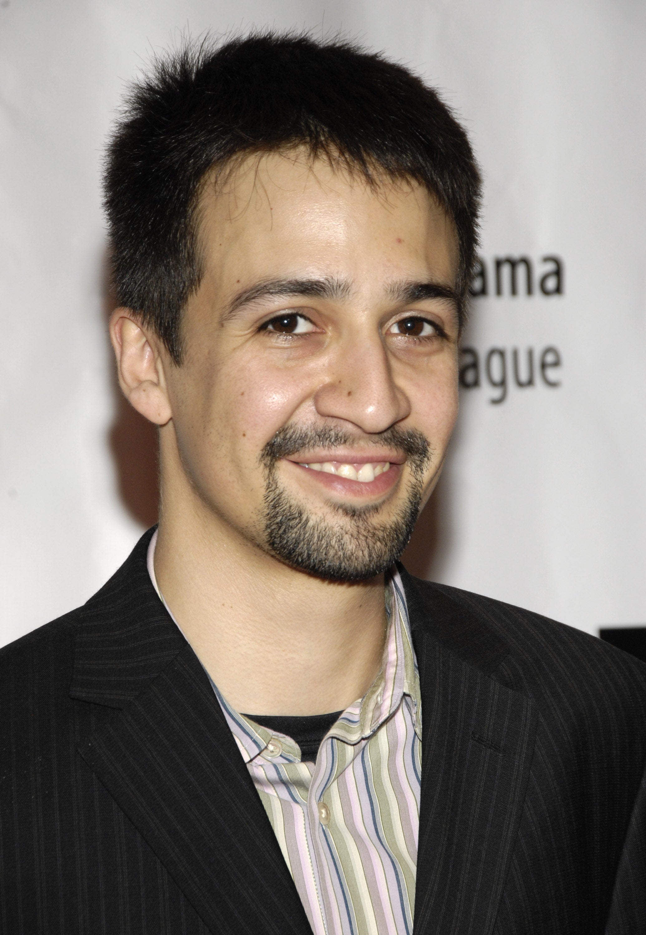 Person in pinstripe suit with striped shirt, casually smiling at an event