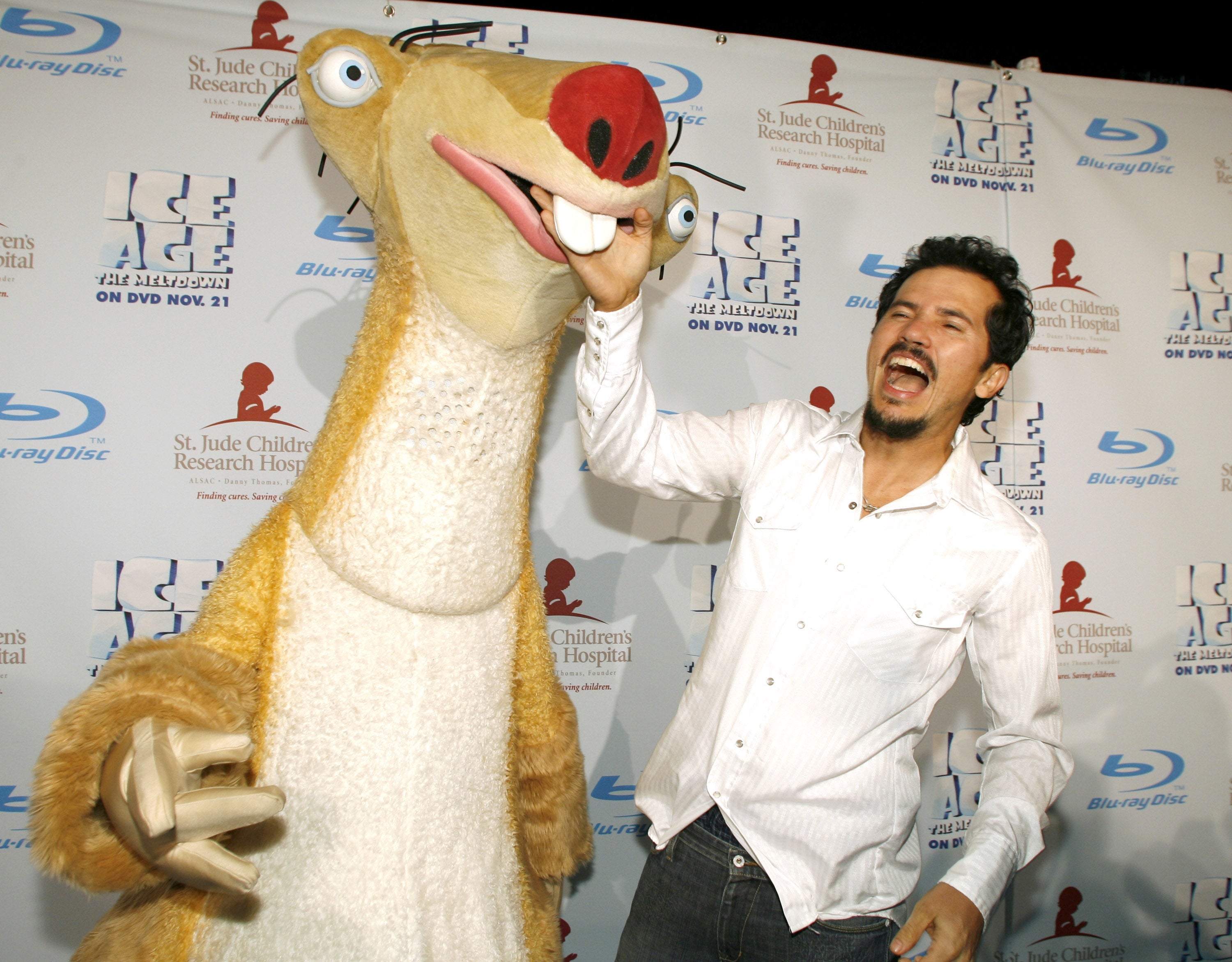 Person poses playfully with a character in a costume at an event promoting "Ice Age" on DVD for St. Jude Children's Research Hospital