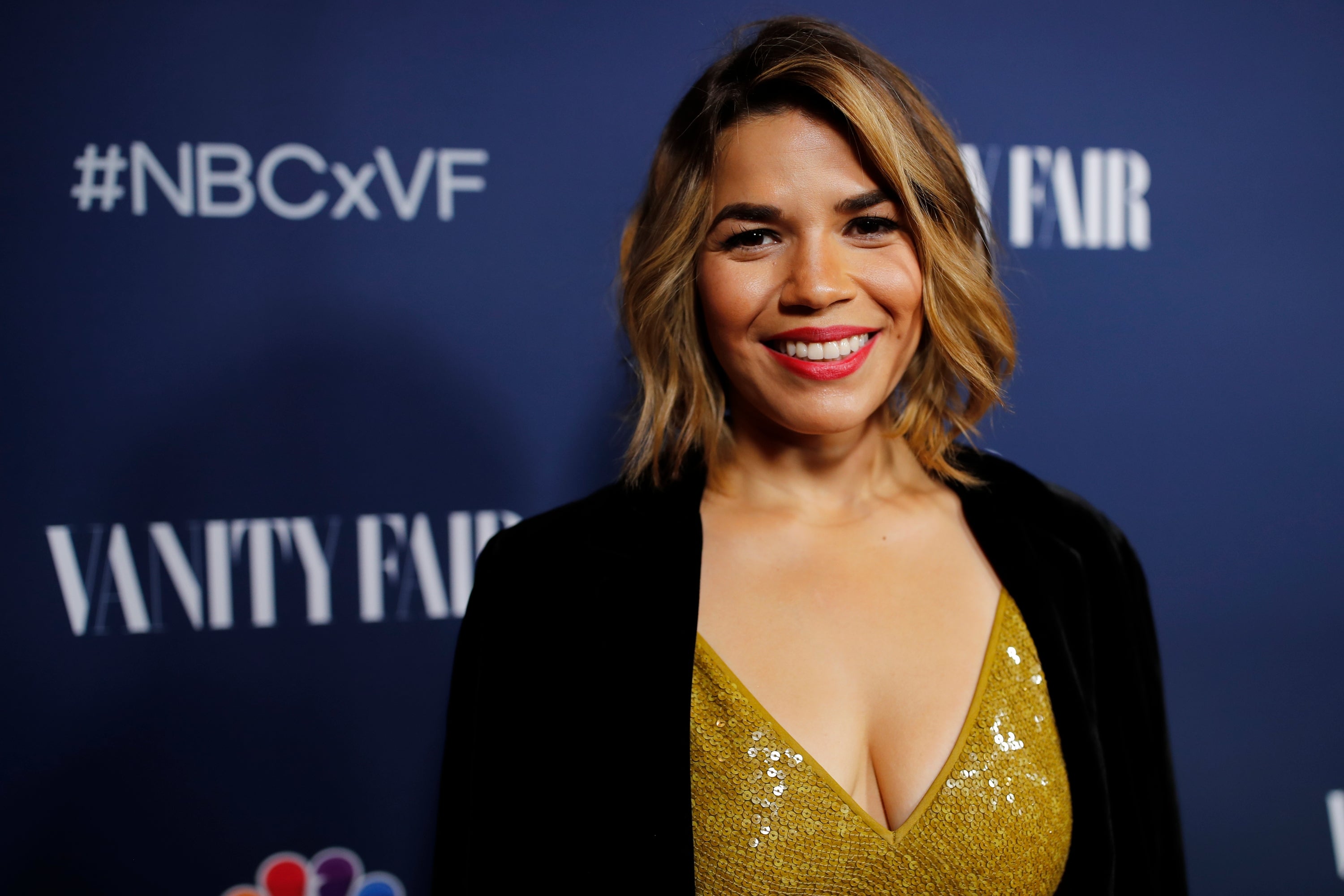 Person smiling at a Vanity Fair event, wearing a stylish outfit with a sequin top and a dark jacket