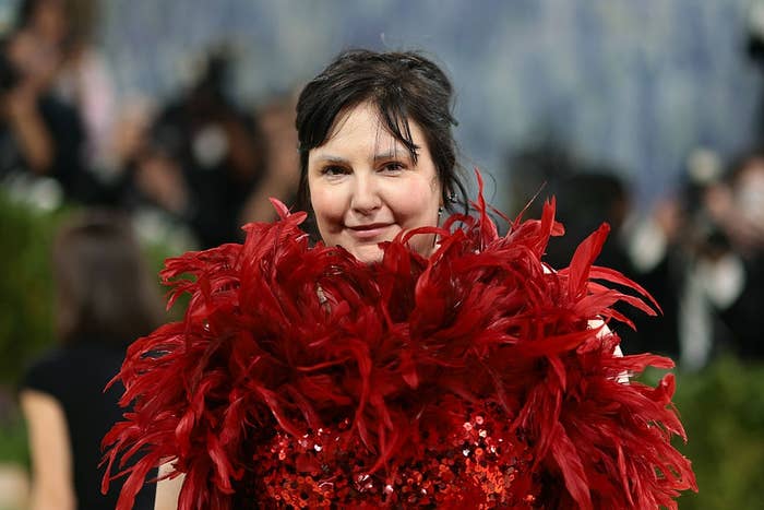 Person on red carpet wearing a dress adorned with large, dramatic feathers