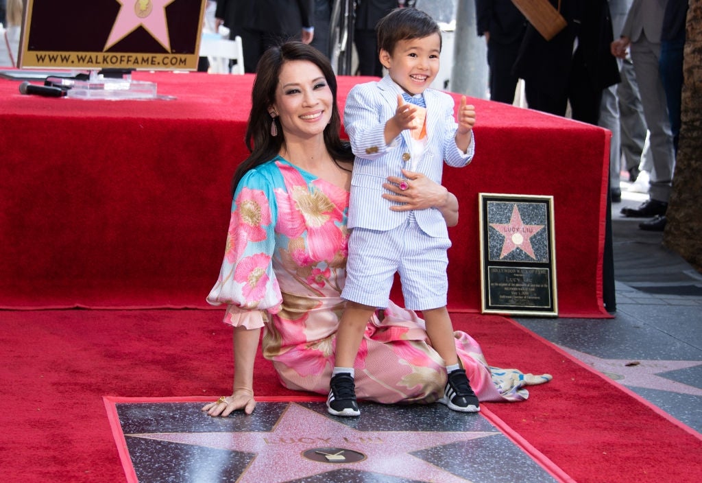 Person in floral dress poses with child next to a Hollywood Walk of Fame star