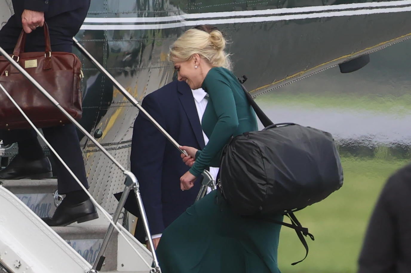 Person i elegant antrekk som går ombord på et fly, bærer på en stor svart bag