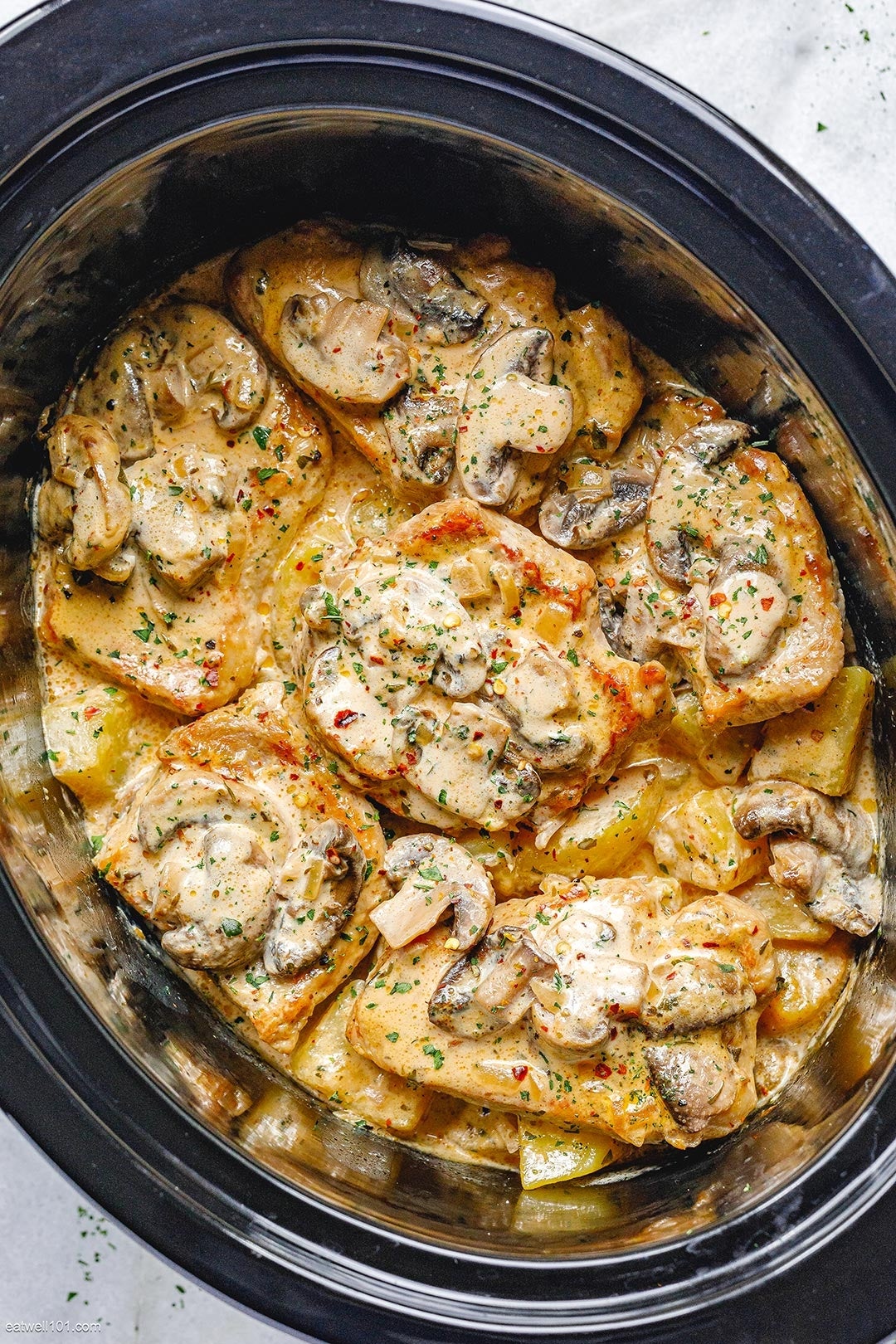 Creamy slow-cooked chicken with mushrooms, topped with herbs, in a slow cooker