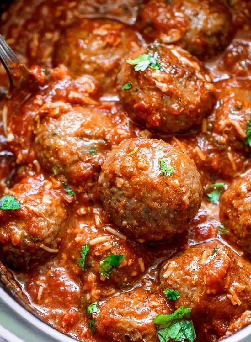 Meatballs in rich tomato sauce garnished with herbs, served in a dish