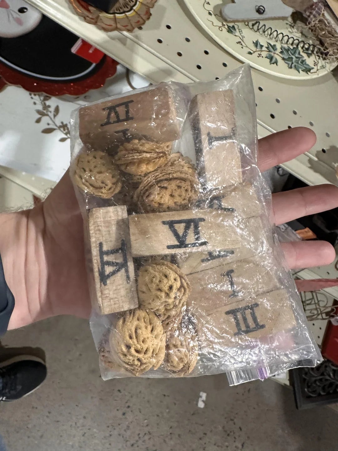 Bag of wooden tiles with Roman numerals and small circular objects, held in a hand in a store