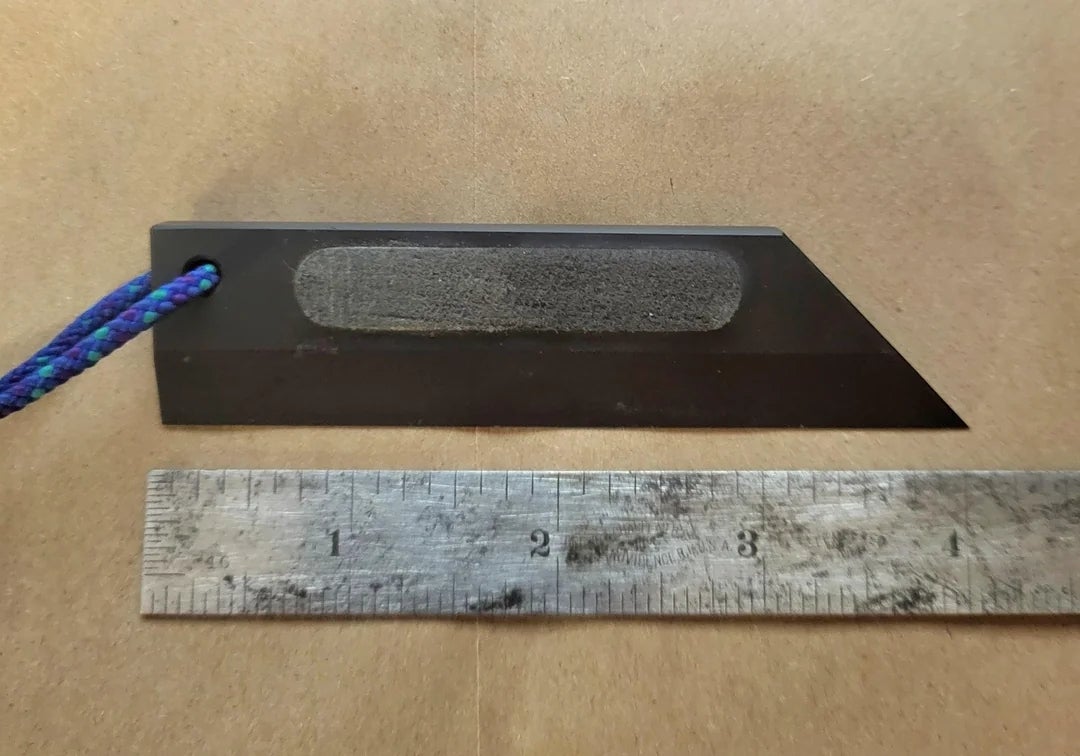 Knife-like object next to a ruler for scale, showing a length of approximately three inches