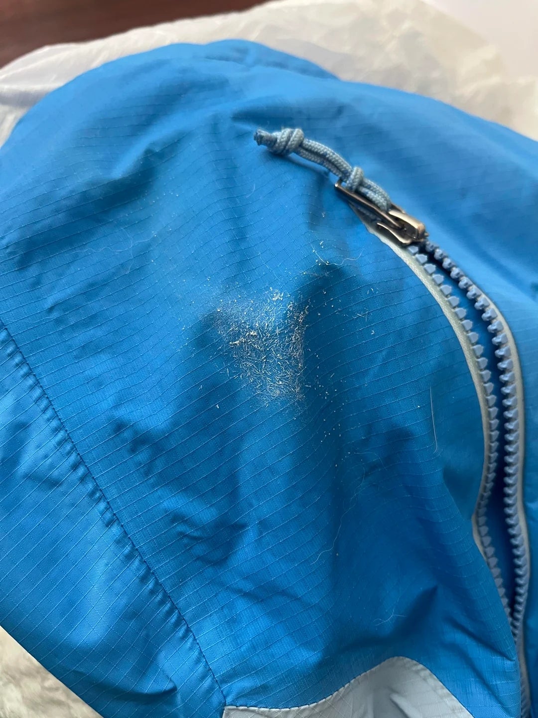 Close-up of a blue jacket with a small area of dirt or dust near the zipper