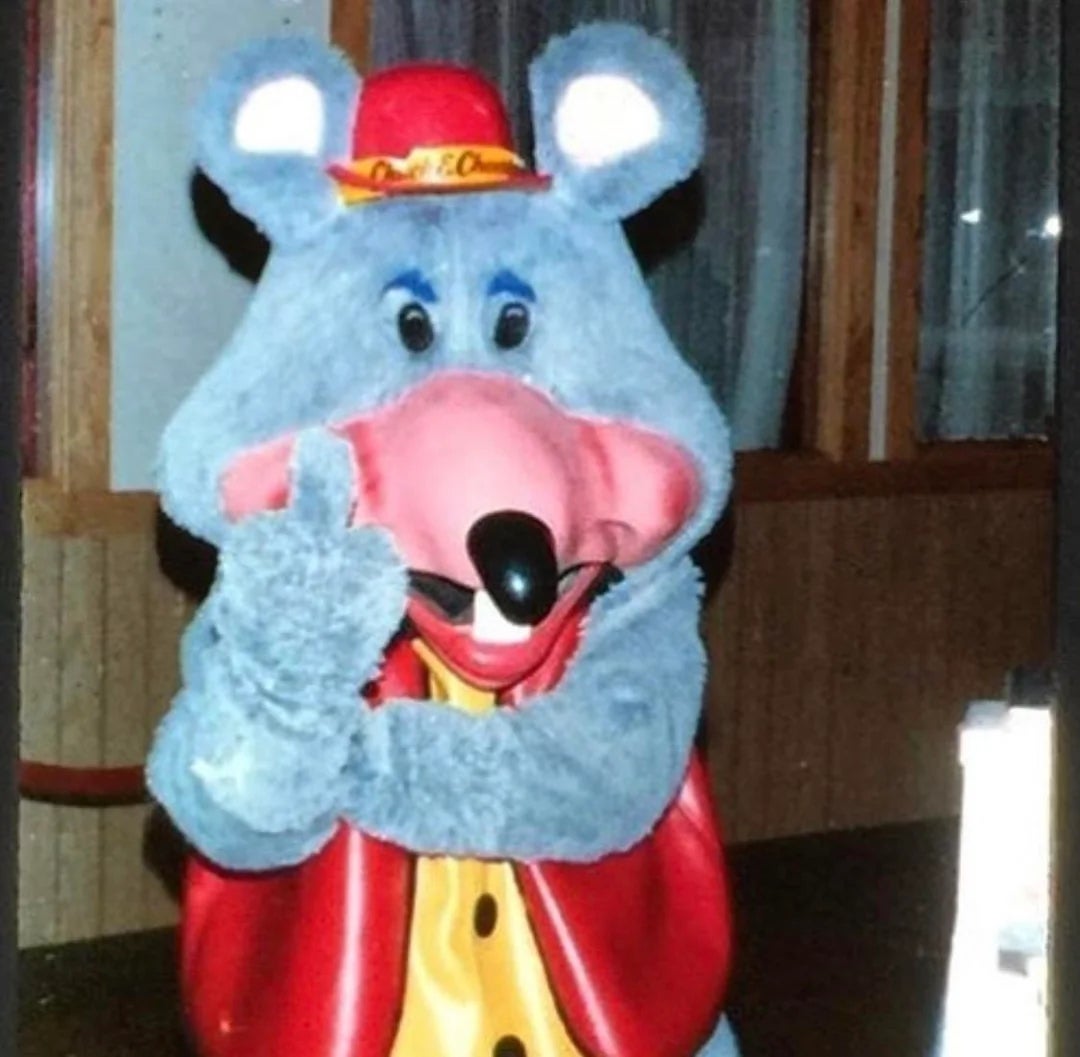 Vintagebilde av en person i et Chuck E Cheese-kostyme som holder opp langfingeren