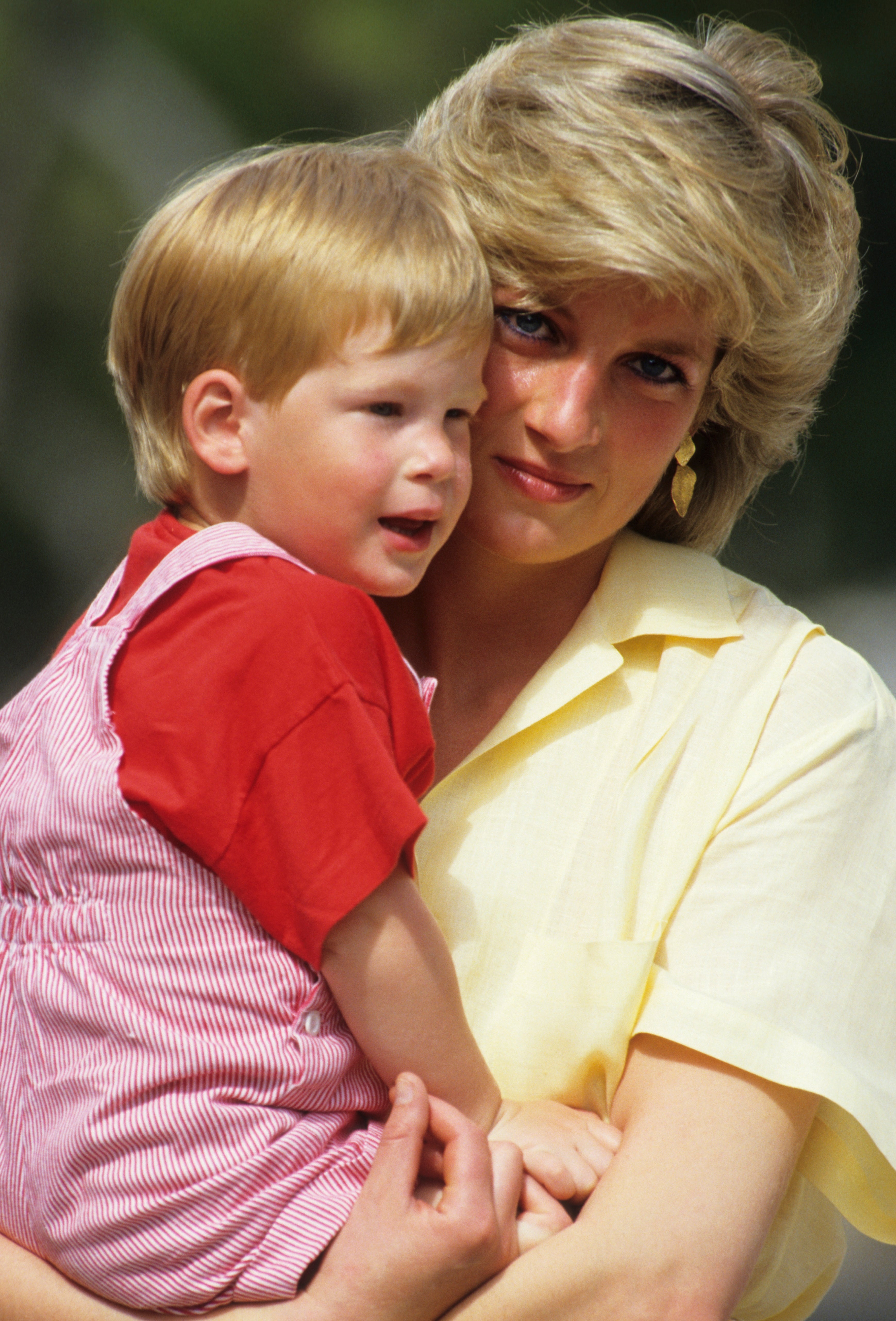 Woman in casual blouse holding a young child in her arms, both looking towards the camera