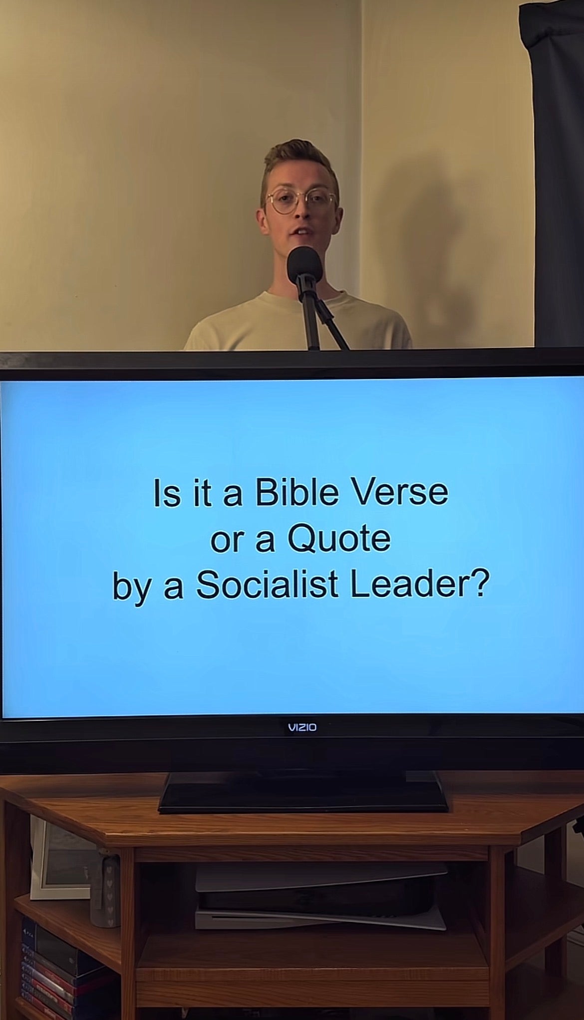 Person som står bak en mikrofon, med en skjerm som viser teksten: "Er det et bibelvers eller et sitat av en sosialistisk leder?"