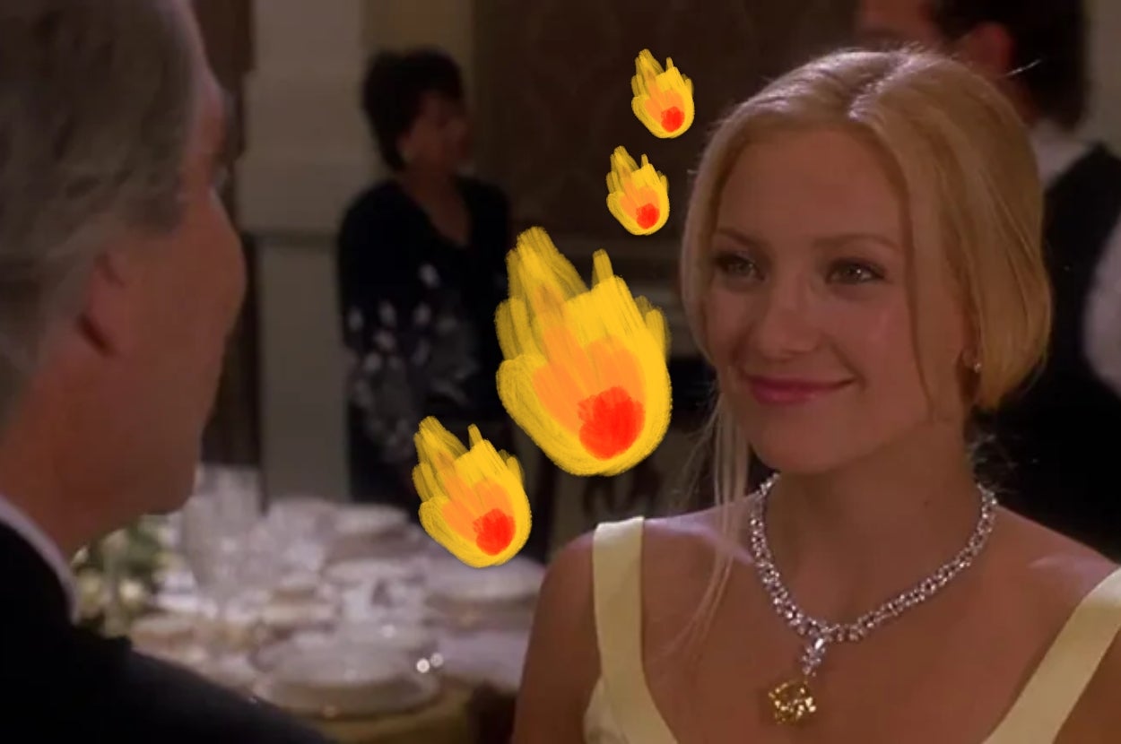 Person in elegant gown with a diamond necklace smiling at another person, with cartoon flames edited in the image