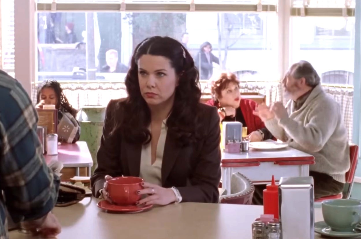 Lorelai Gilmore sits at a diner counter holding a mug