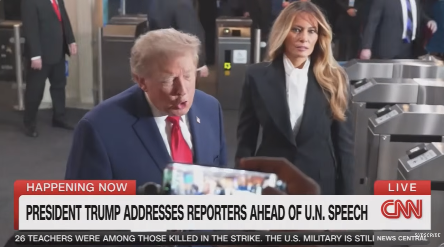En mann i dress henvender seg til journalister, mens en kvinne i formelt antrekk står i nærheten. CNN nyhetsbanner rapporterer om en tale i FN