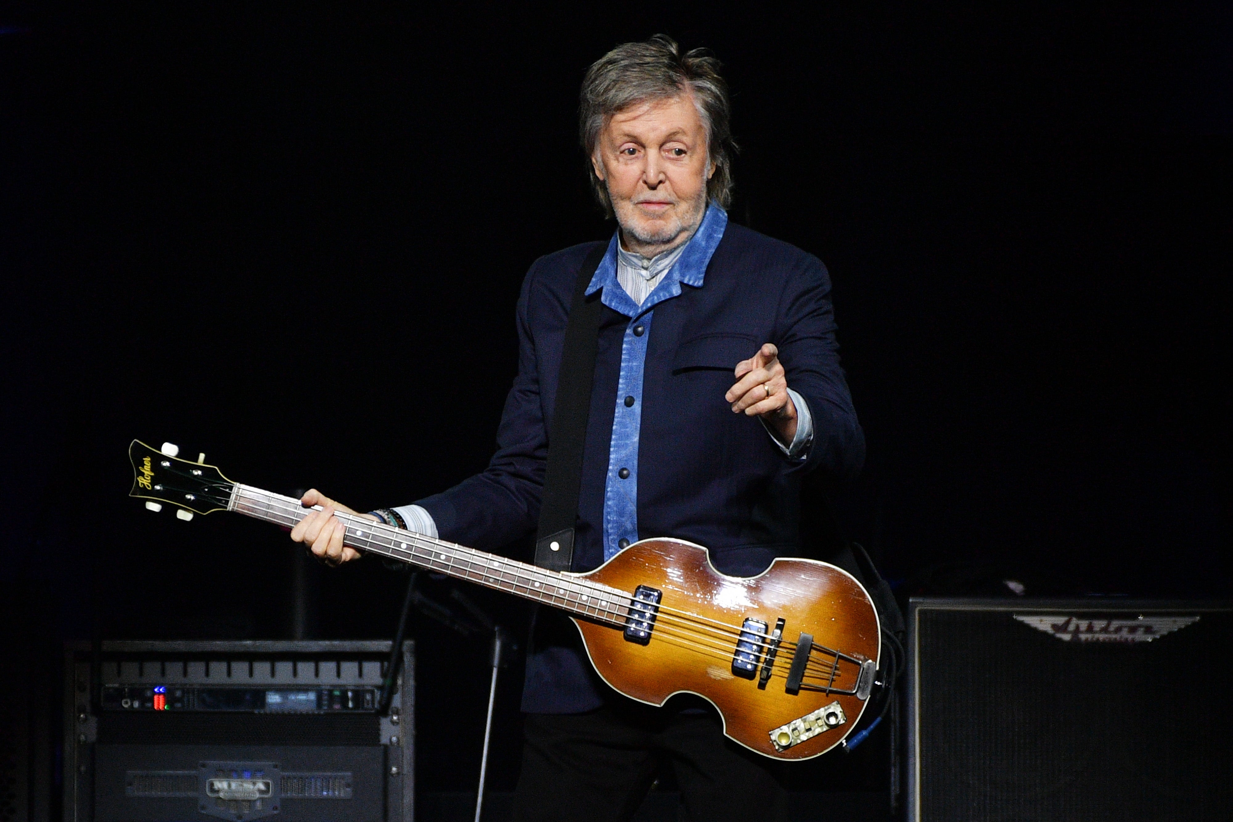 Musician playing guitar on stage wearing a layered denim and jacket outfit