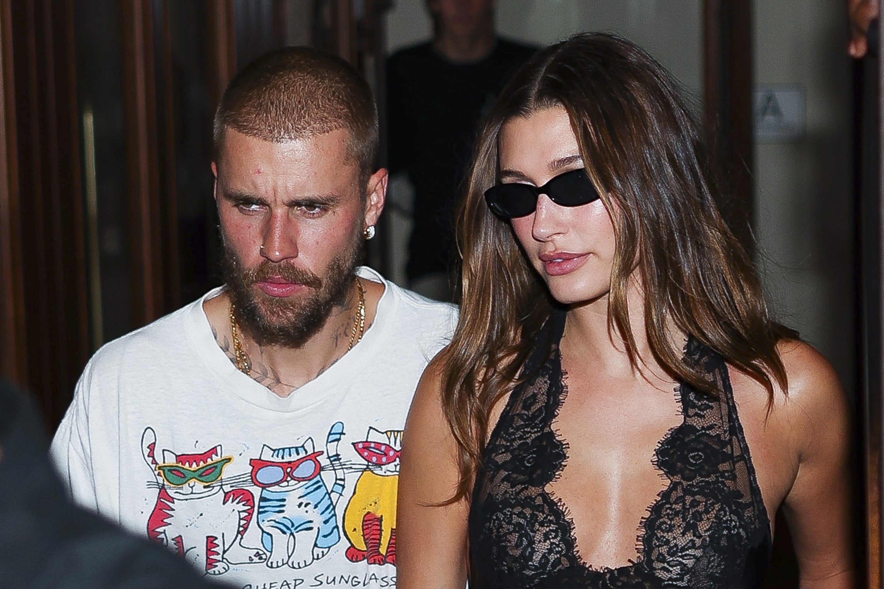 Two people walking together. One wears a casual T-shirt with colorful graphics, the other wears a stylish lace-patterned top and sunglasses