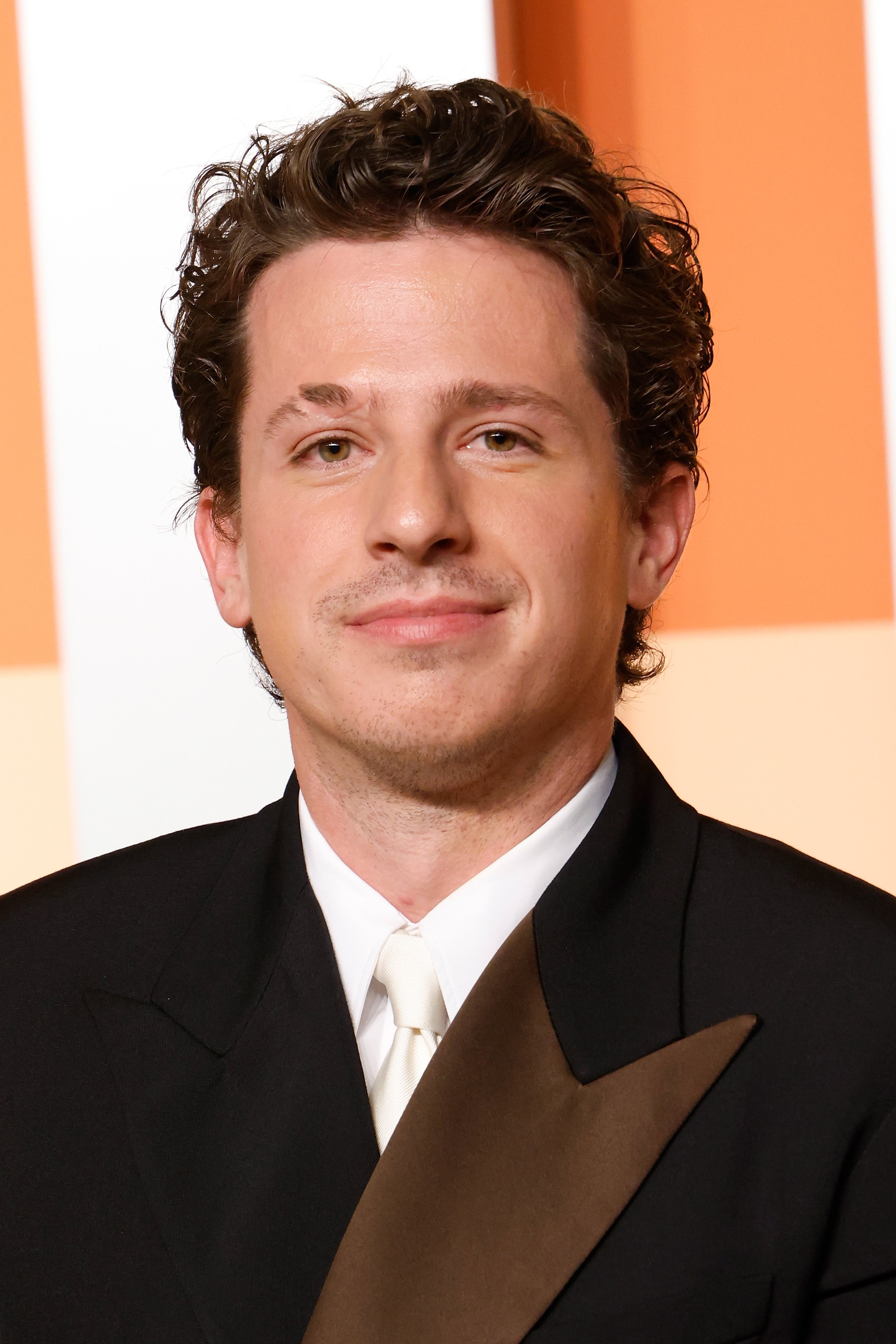 Person in formal attire with a double-breasted blazer and tie, smiling at an event