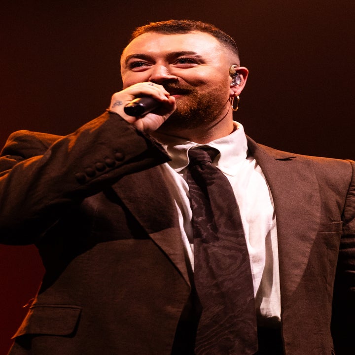 Person in a suit singing into a microphone on stage
