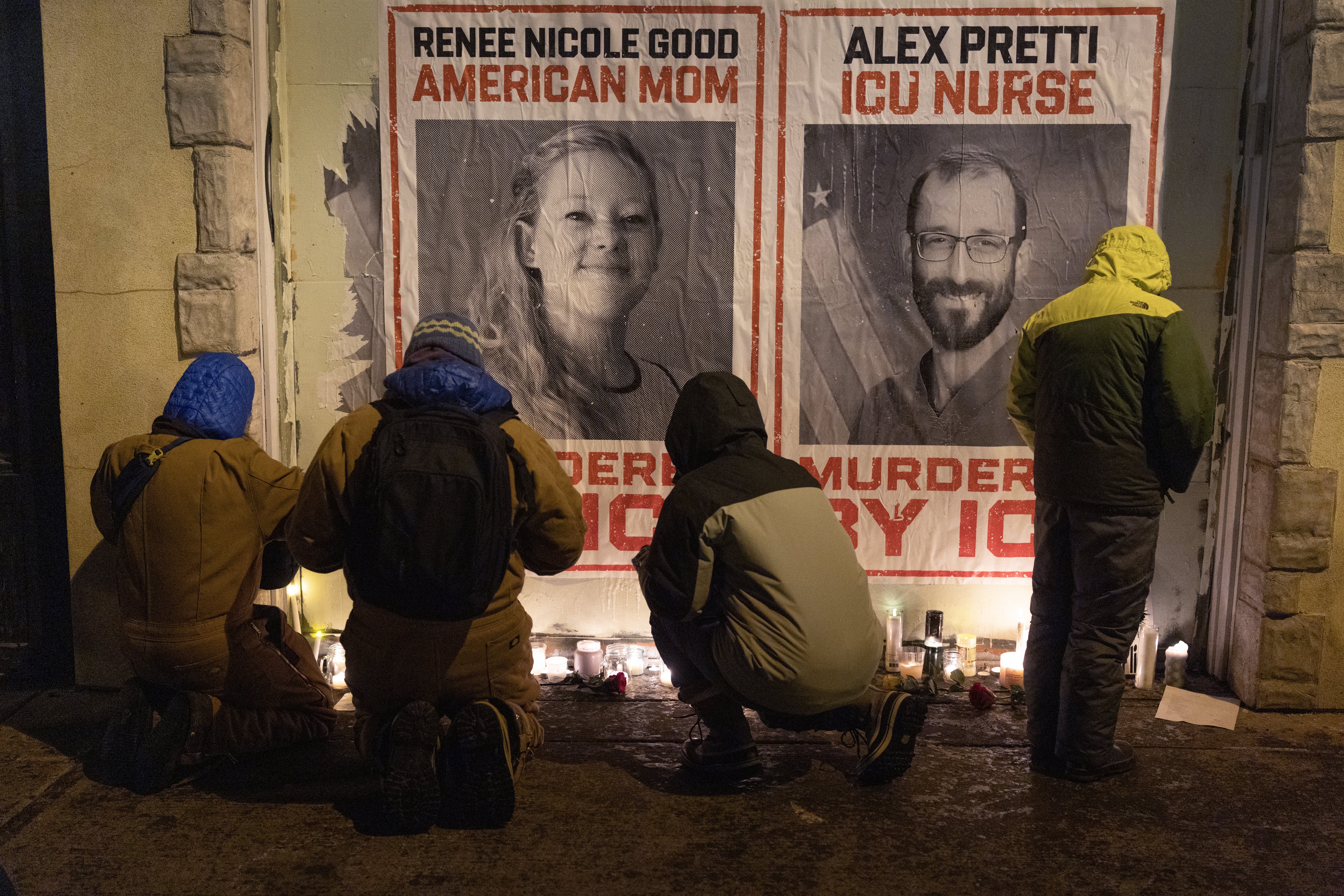 Fire personer kneler og tenner lys ved plakater for Renee Nicole Good og Alex Pretti, merket