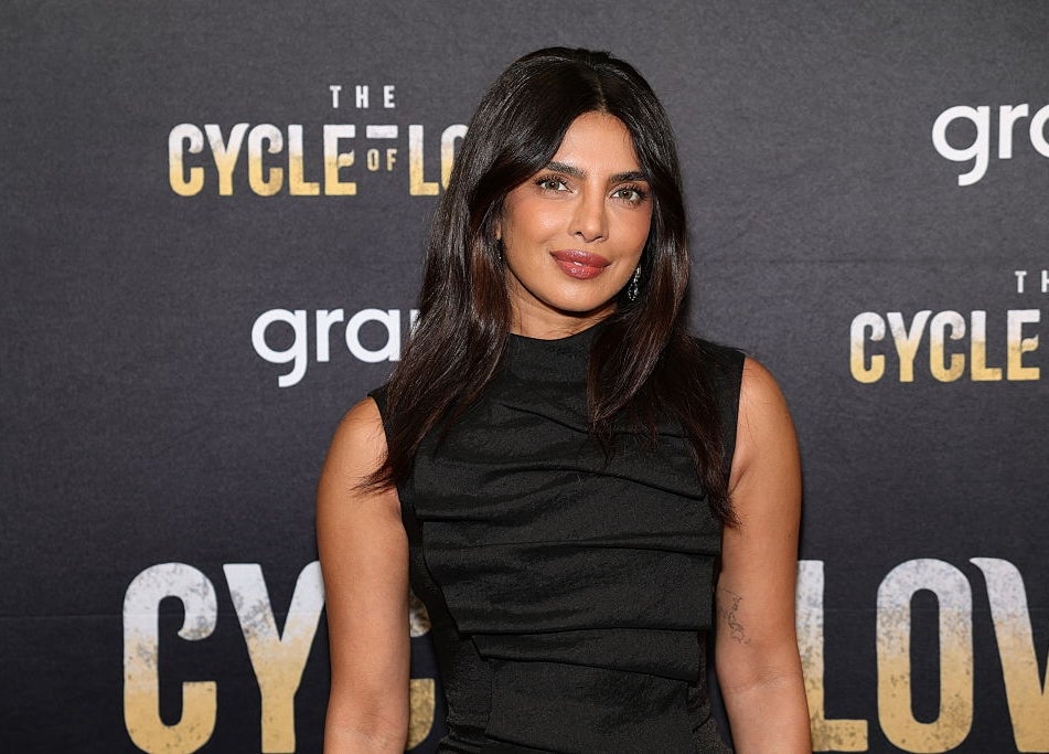 Celebrity on a red carpet, wearing a sleek black sleeveless dress, attends an event for "The Cycle of Love."