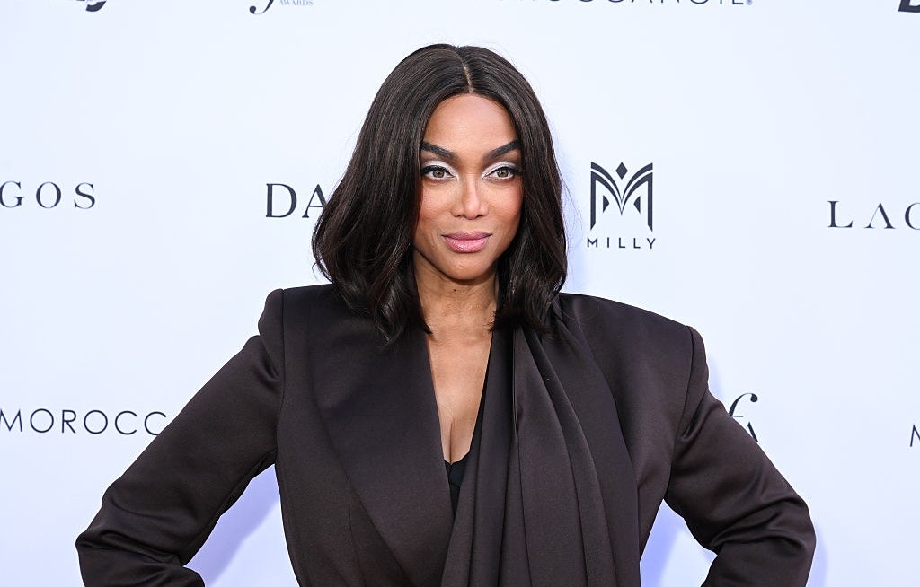 A person posing on the red carpet in stylish formal attire, featuring a structured, dark blazer with a confident expression