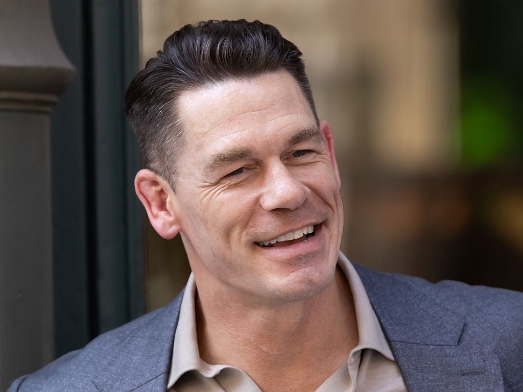 A person in a suit smiles warmly while attending an event