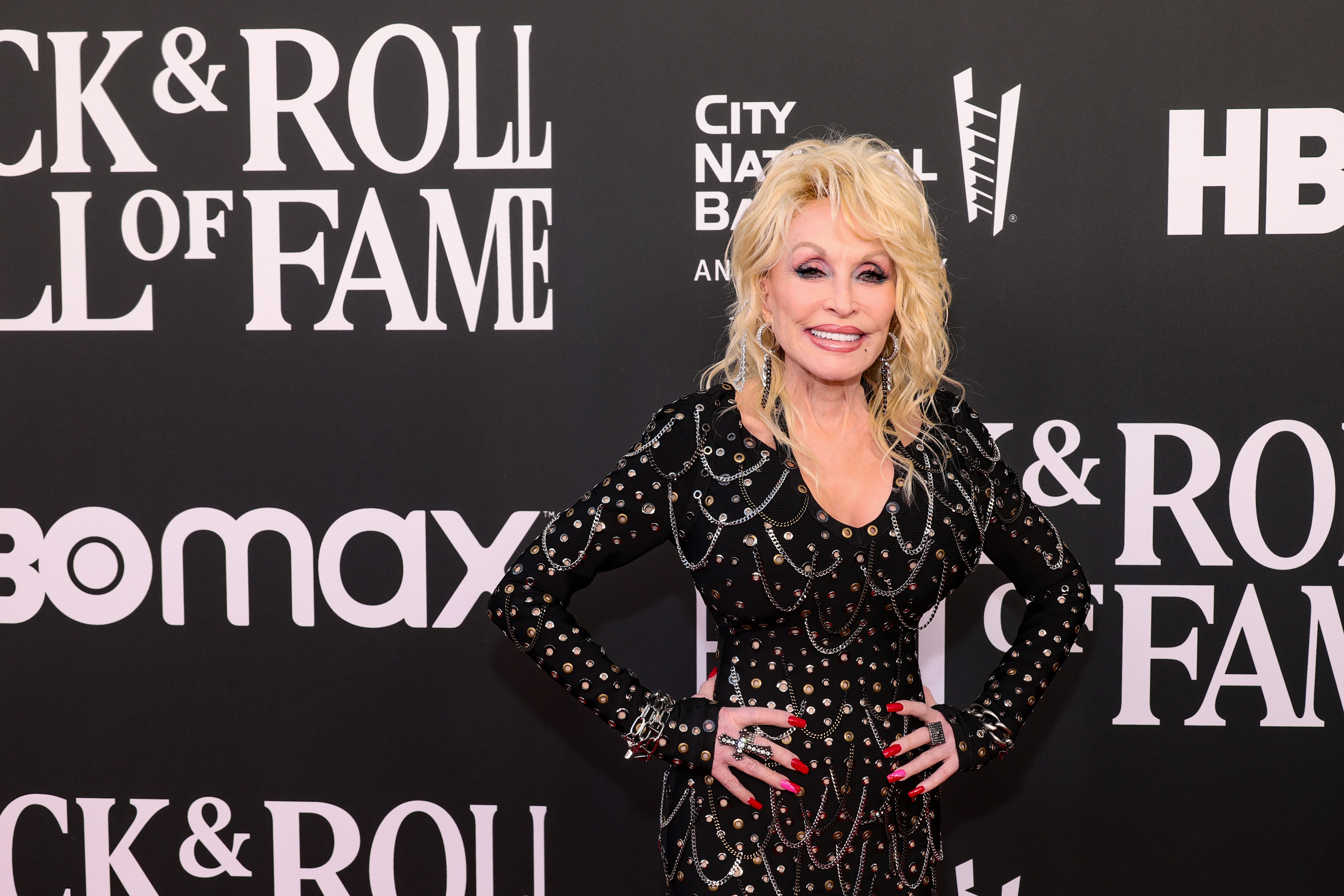 Person i stilig piggdrakt på rød løper på et arrangement, stående foran Rock & Roll Hall of Fame bakteppe