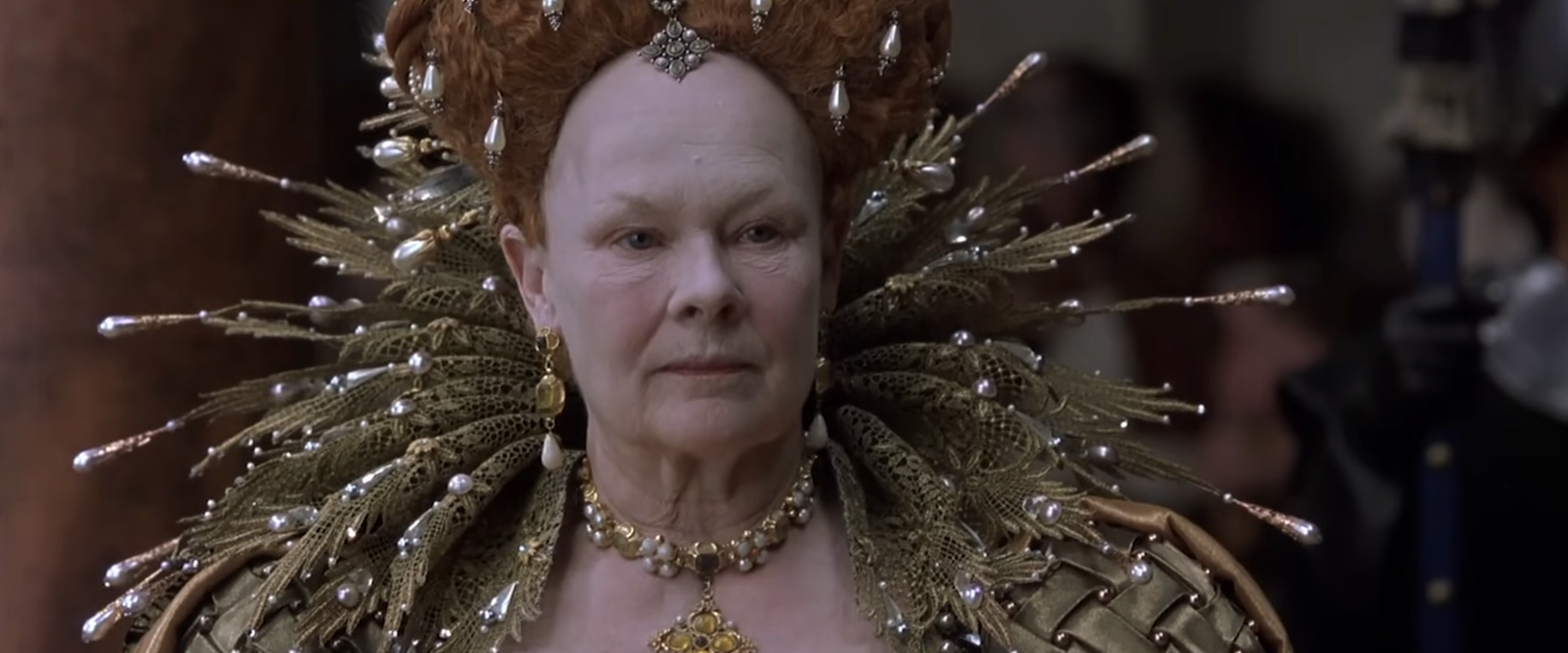 Person in an elaborate period costume with ornate headpiece and jeweled collar, resembling a historical or royal figure