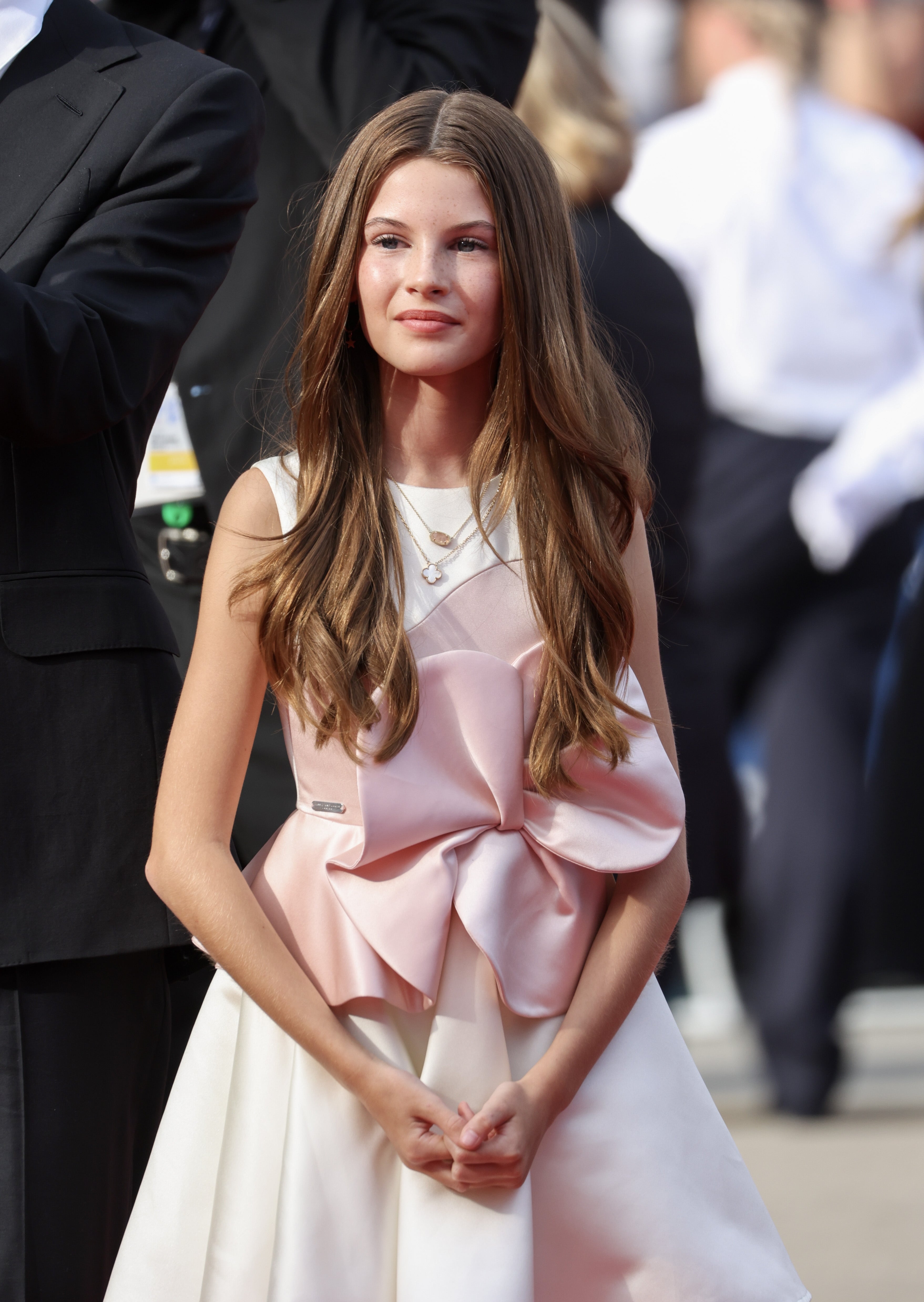 Young woman in a stylish gown with a large decorative bow on the front, standing confidently on the red carpet