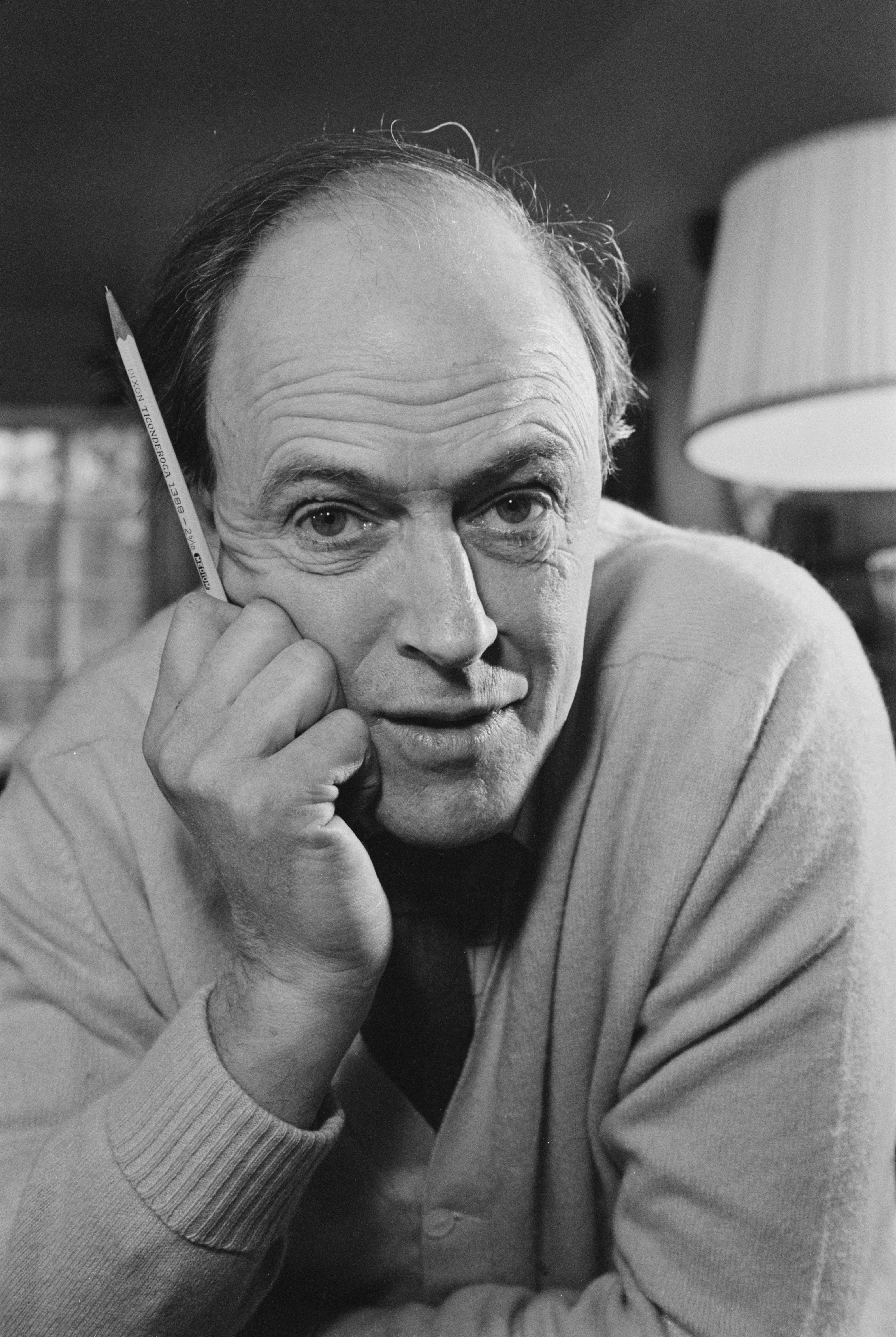 Person resting head on hand, holding a pencil, wearing a sweater, indoors