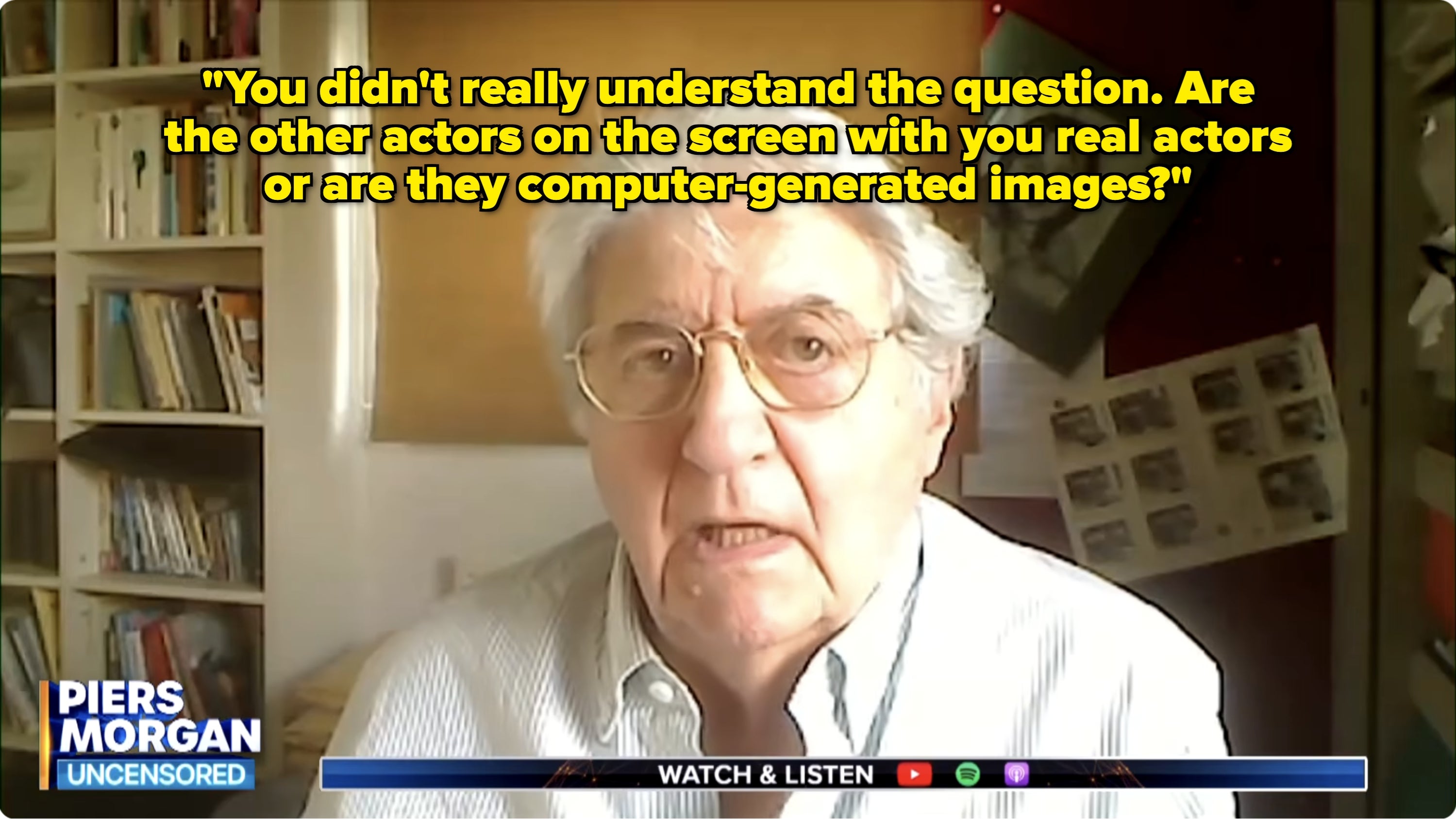 An older person in glasses speaking during an interview on "Piers Morgan Uncensored," with books and photos visible in the background