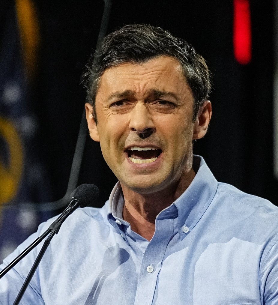 Jon Ossoff i en sammenrullet skjorte snakker lidenskapelig på et podium med en