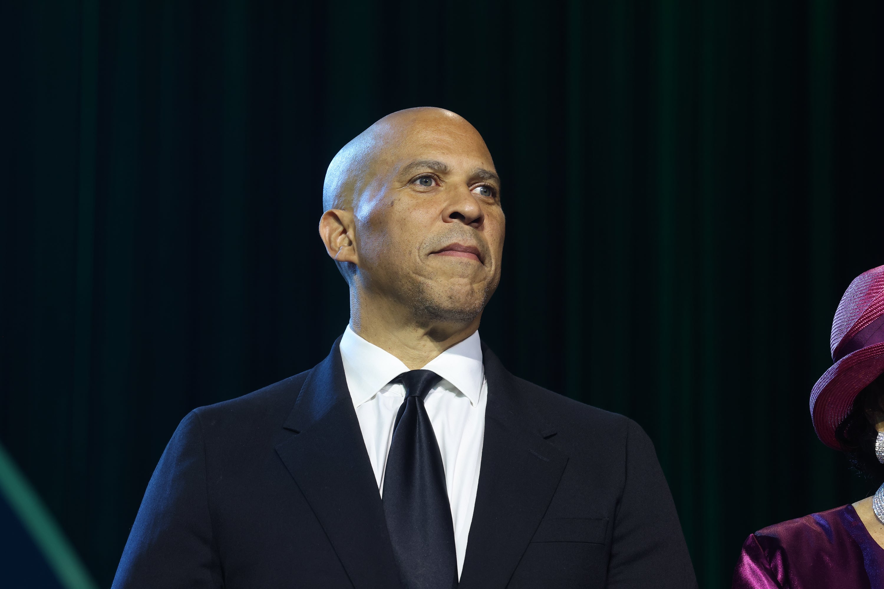 Cory Booker i dress og slips står på scenen og ser gjennomtenkt ut