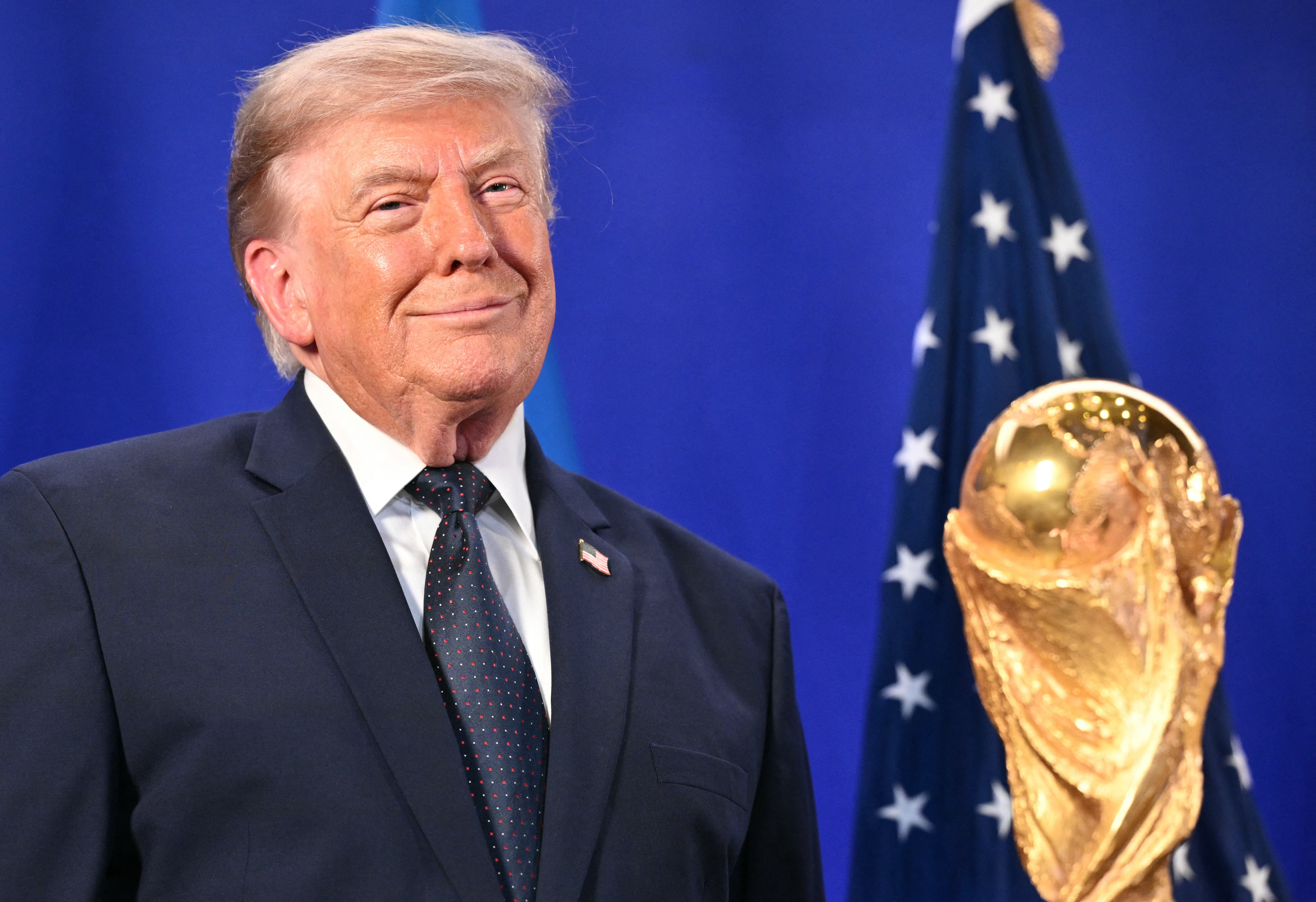 Donald Trump smiler på scenen ved siden av det gylne troféet