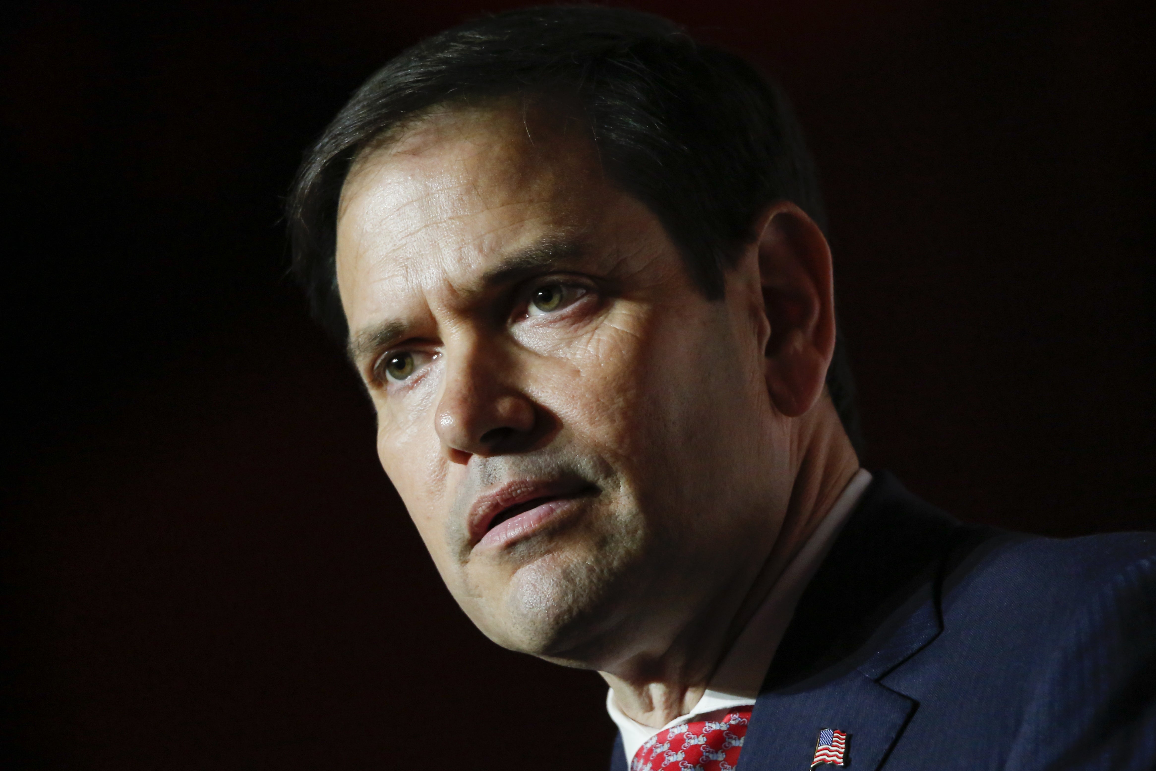 Marco Rubio skuler mot en mørk, dramatisk bakgrunn