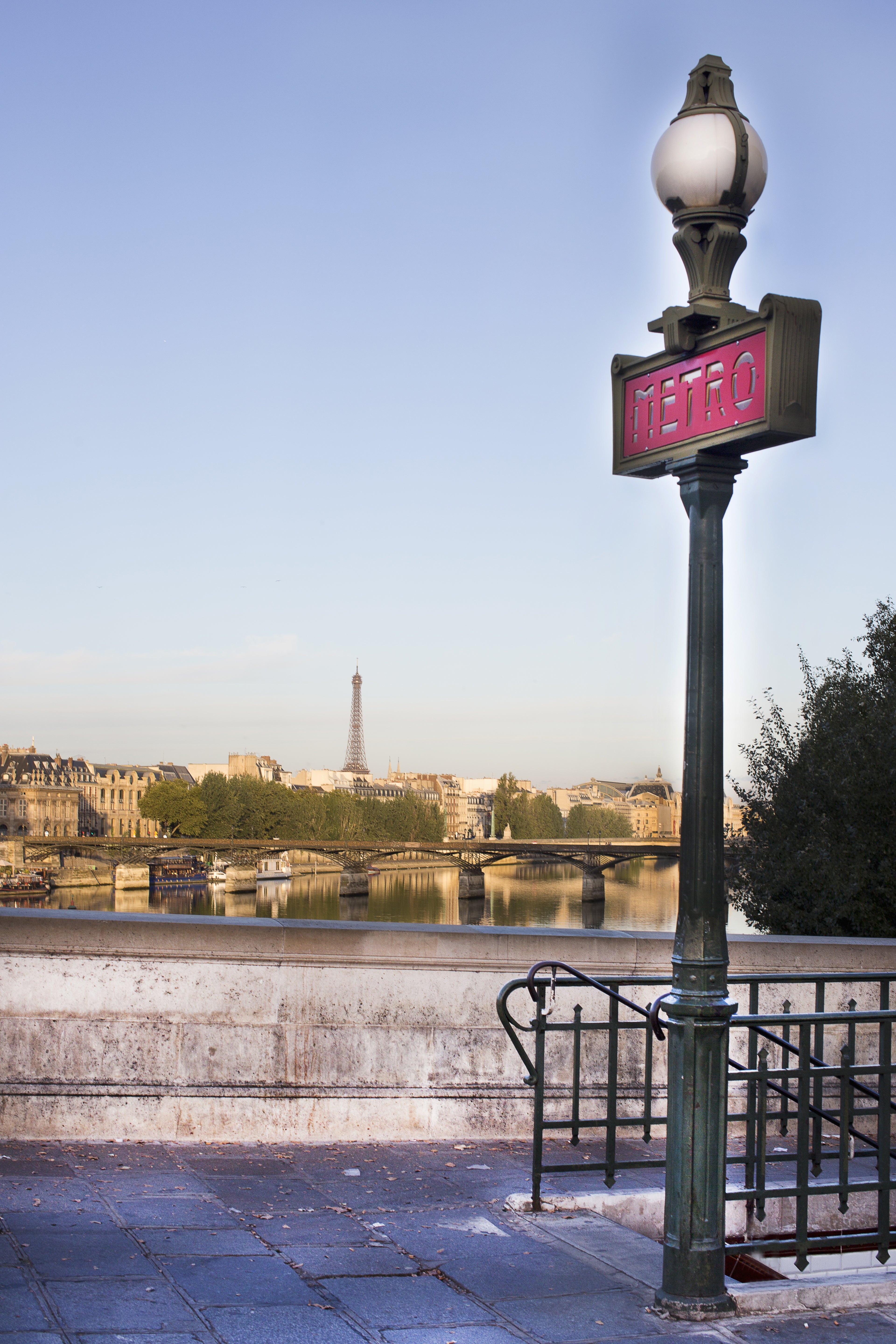 View of the Parisian skyline with Eiffel Tower, Seine River, and Metro sign in foreground, showcasing iconic travel landmarks