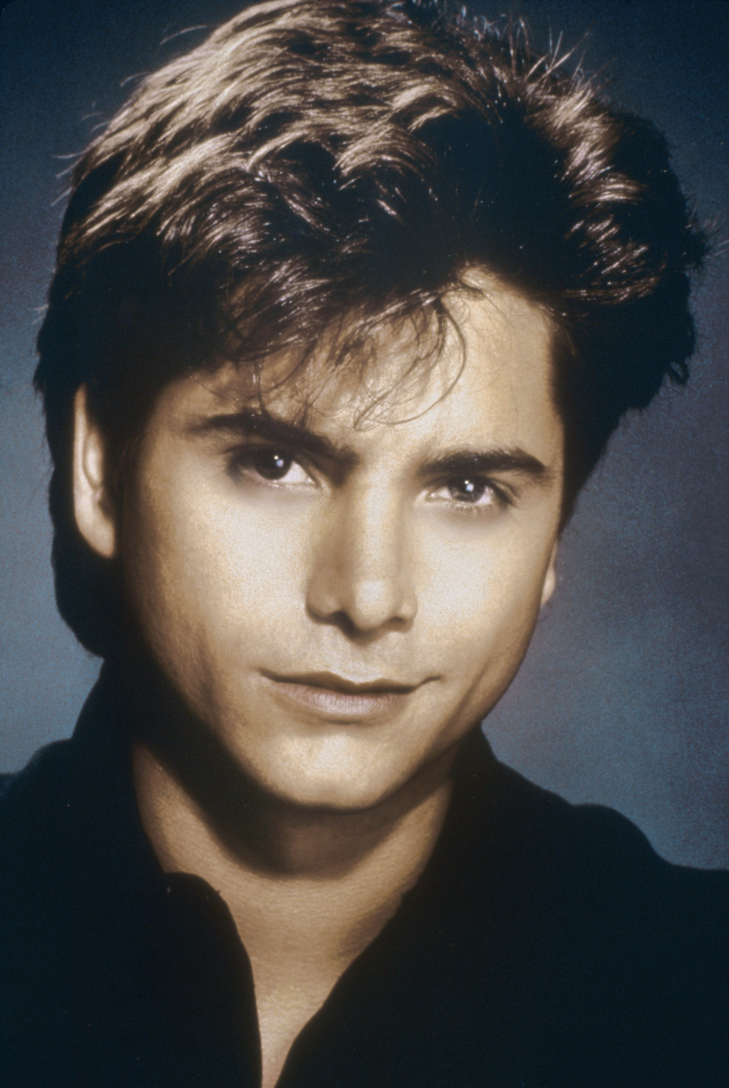 A person with styled hair and a confident expression looks toward the camera