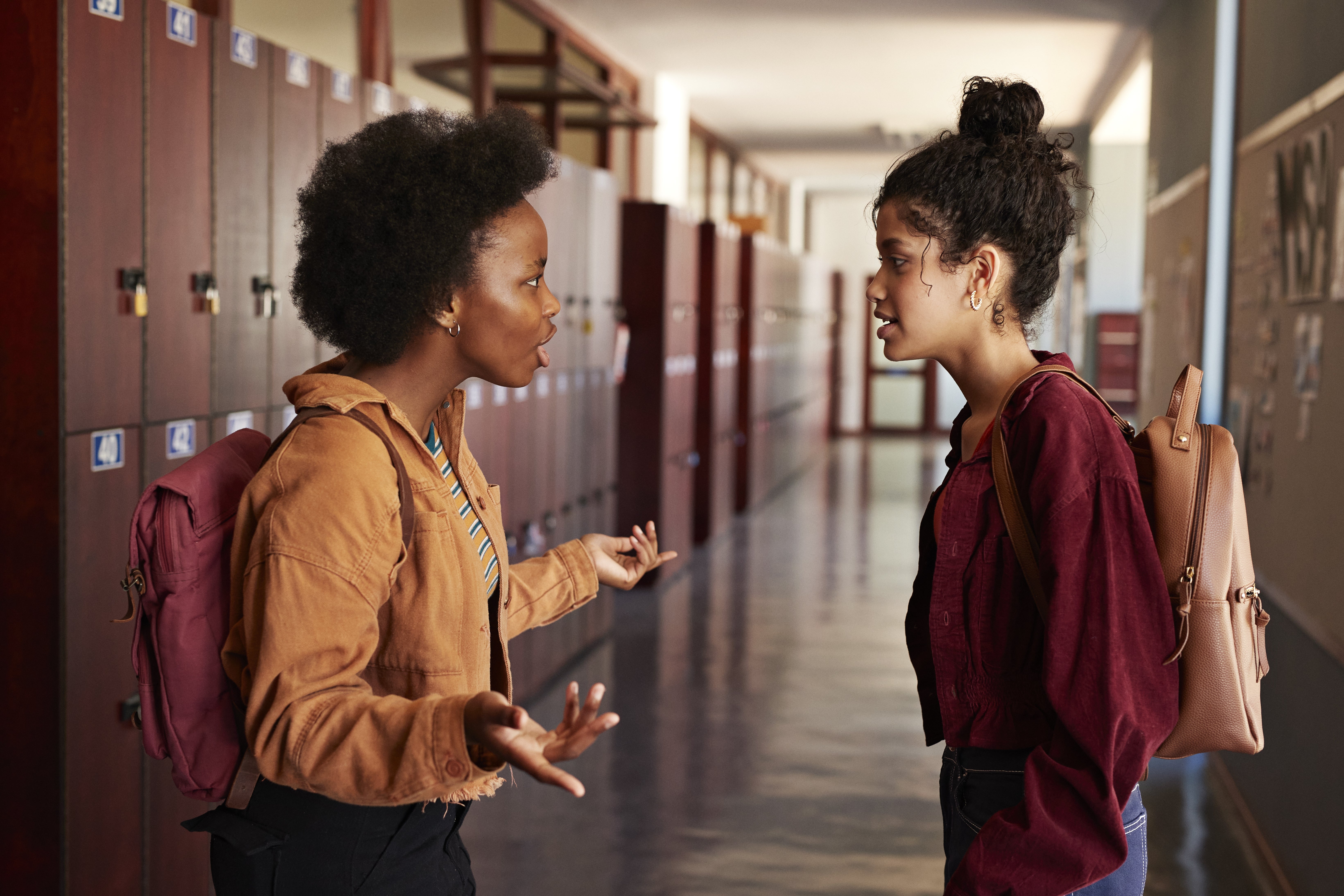 Two people with backpacks have a fight in a school hallway