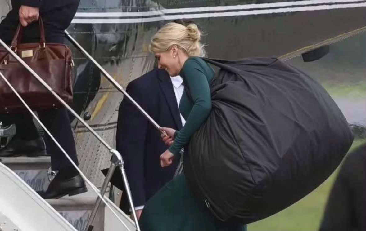 Person i elegant antrekk går opp flytrapper, bærende på en overdimensjonert svart bag