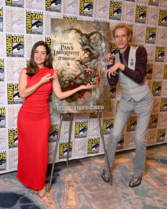 Two individuals airs  adjacent  to a "Pan's Labyrinth 20th Anniversary" poster astatine  a Comic-Con event. The pistillate   wears a sleeveless dress; the antheral   is successful  a vest and pants