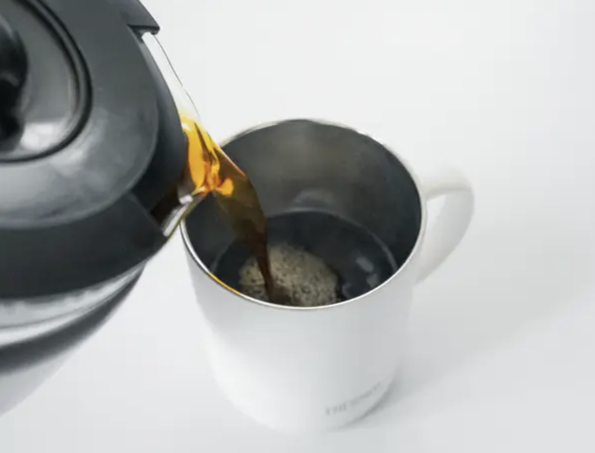 コーヒーポットから湯気を立ててコーヒーカップに淹れている様子。
