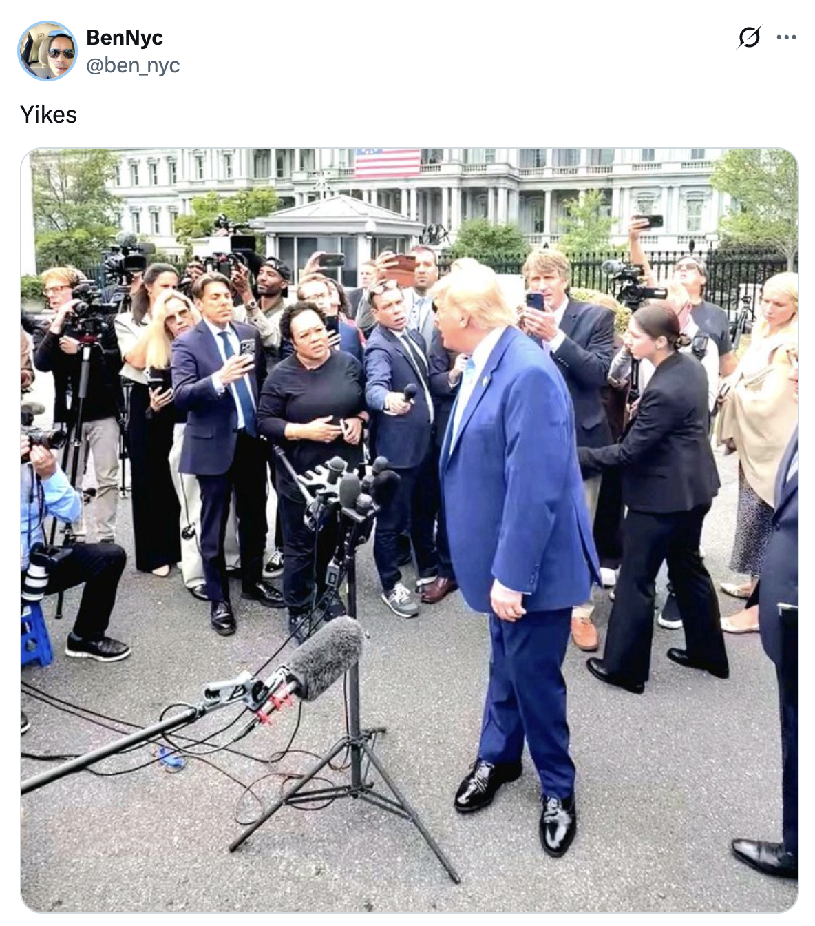En person i dress snakker til en mengde journalister og fotografer samlet rundt med mikrofoner utenfor en regjeringsbygning