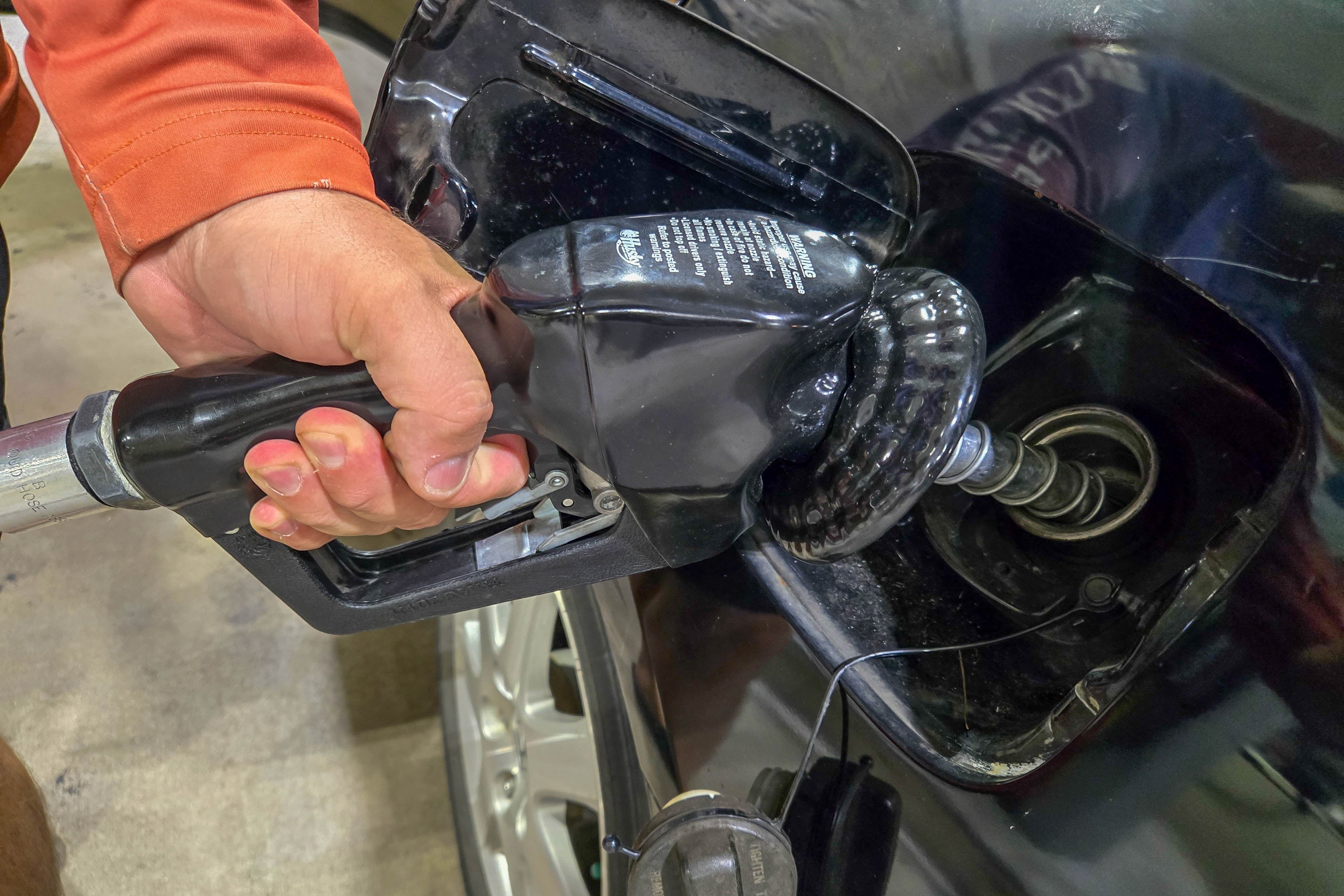 Person som pumper gass inn i en bil på en bensinstasjon