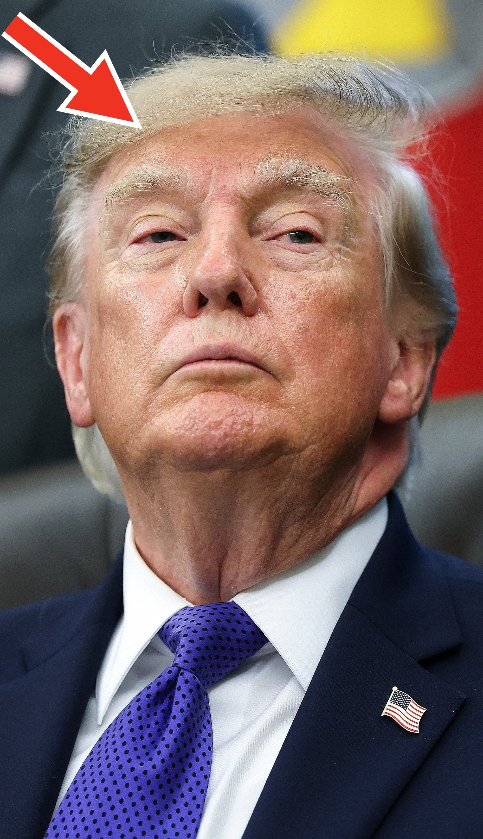 Trump i dress sitter i offisielle omgivelser og ser litt til siden. Et amerikansk flagg er synlig i bakgrunnen