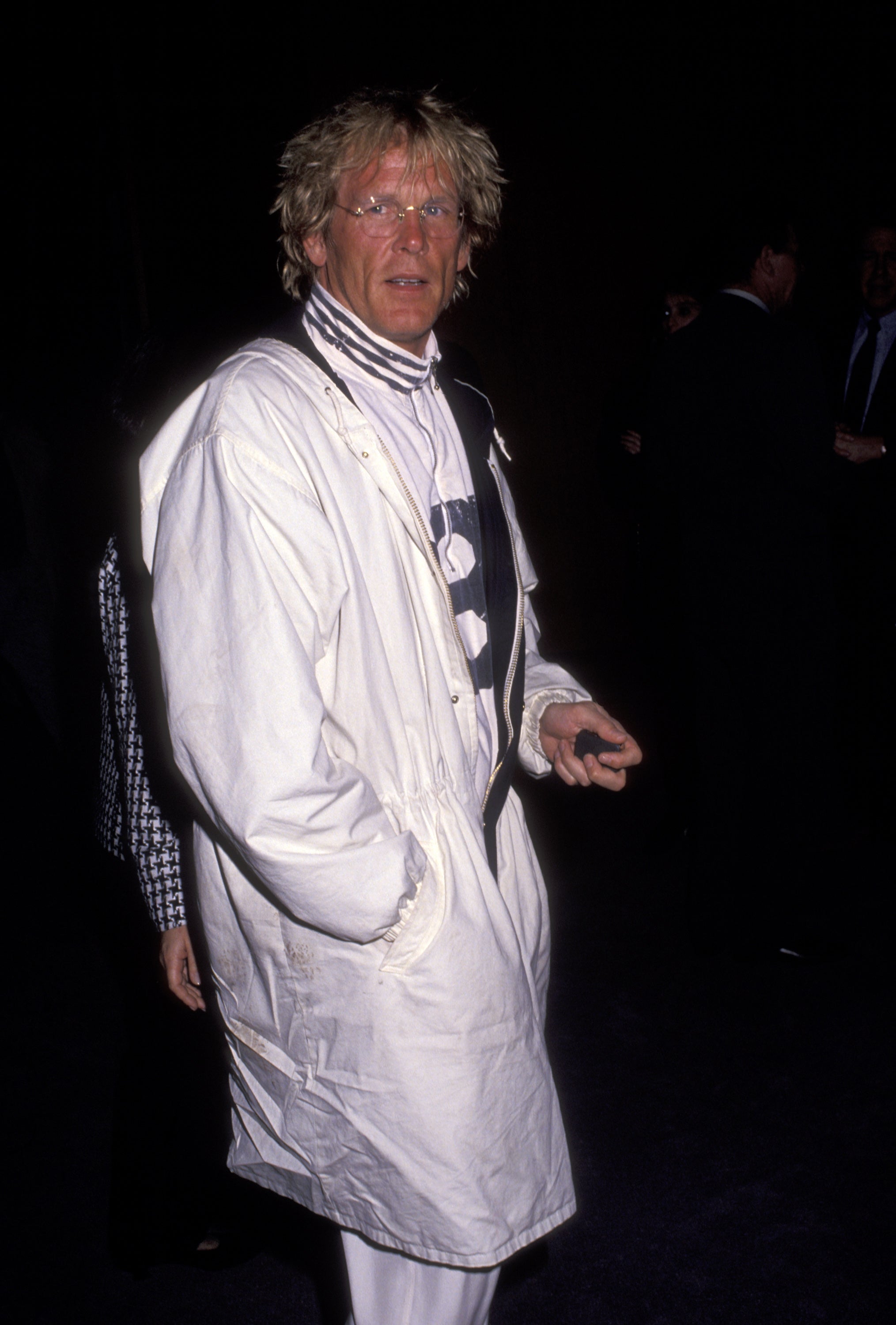 Person in a long, casual coat with a striped turtleneck underneath at a public event