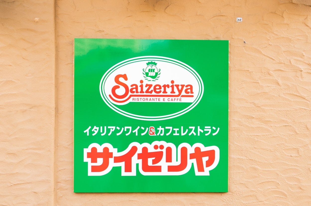 飲食店「サイゼリヤ」の看板が壁に掛かっている。ロゴと店名が目立つデザイン。