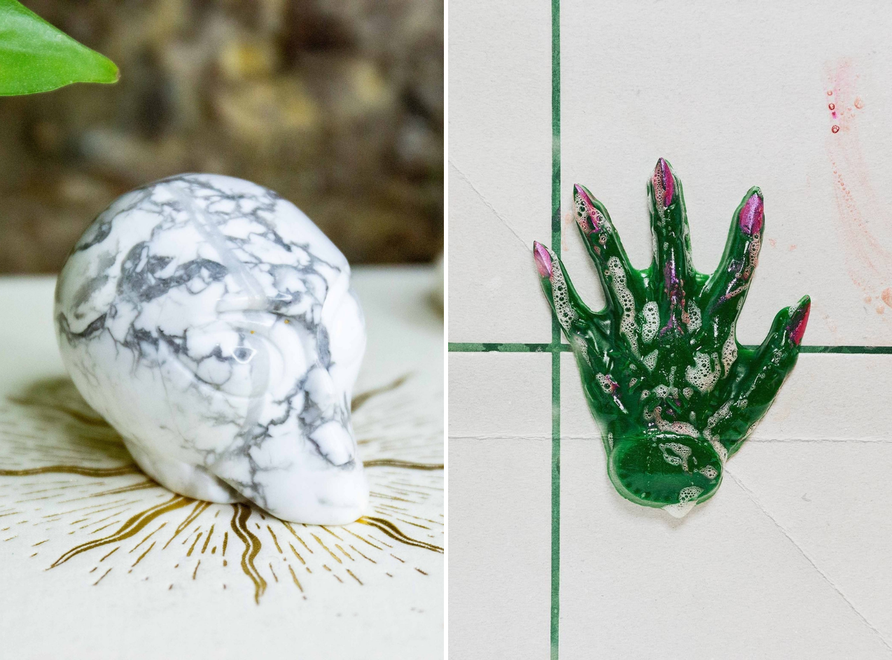 Marble-like stone shaped like a bear alongside a green, ornate sculpture resembling a hand on a tiled surface