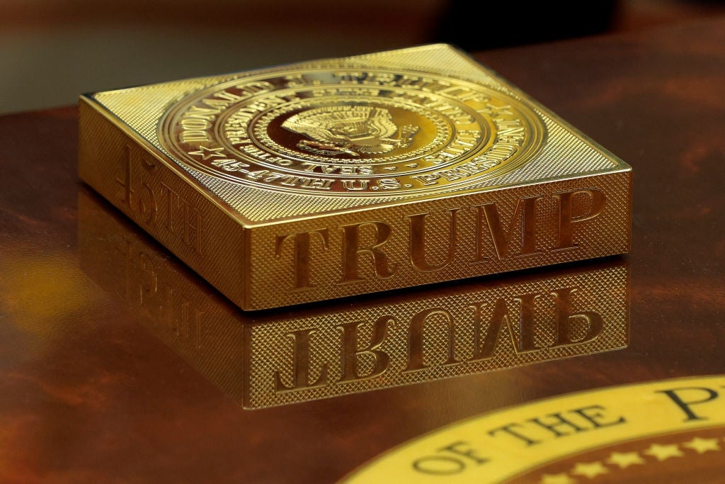 En gullbelagt "TRUMP" sjokoladeplate med en presidentforseglingsdetalj, hvilende på en reflekterende overflate