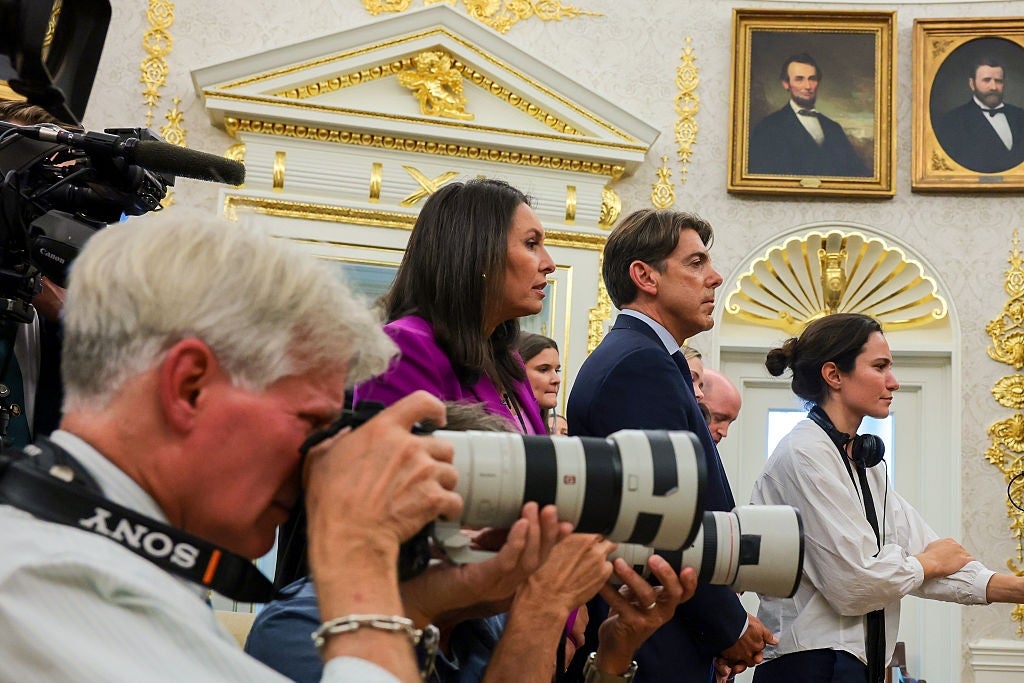 En gruppe journalister i et rom med utsmykket dekor og historiske portretter, noen tar bilder og notater under et arrangement